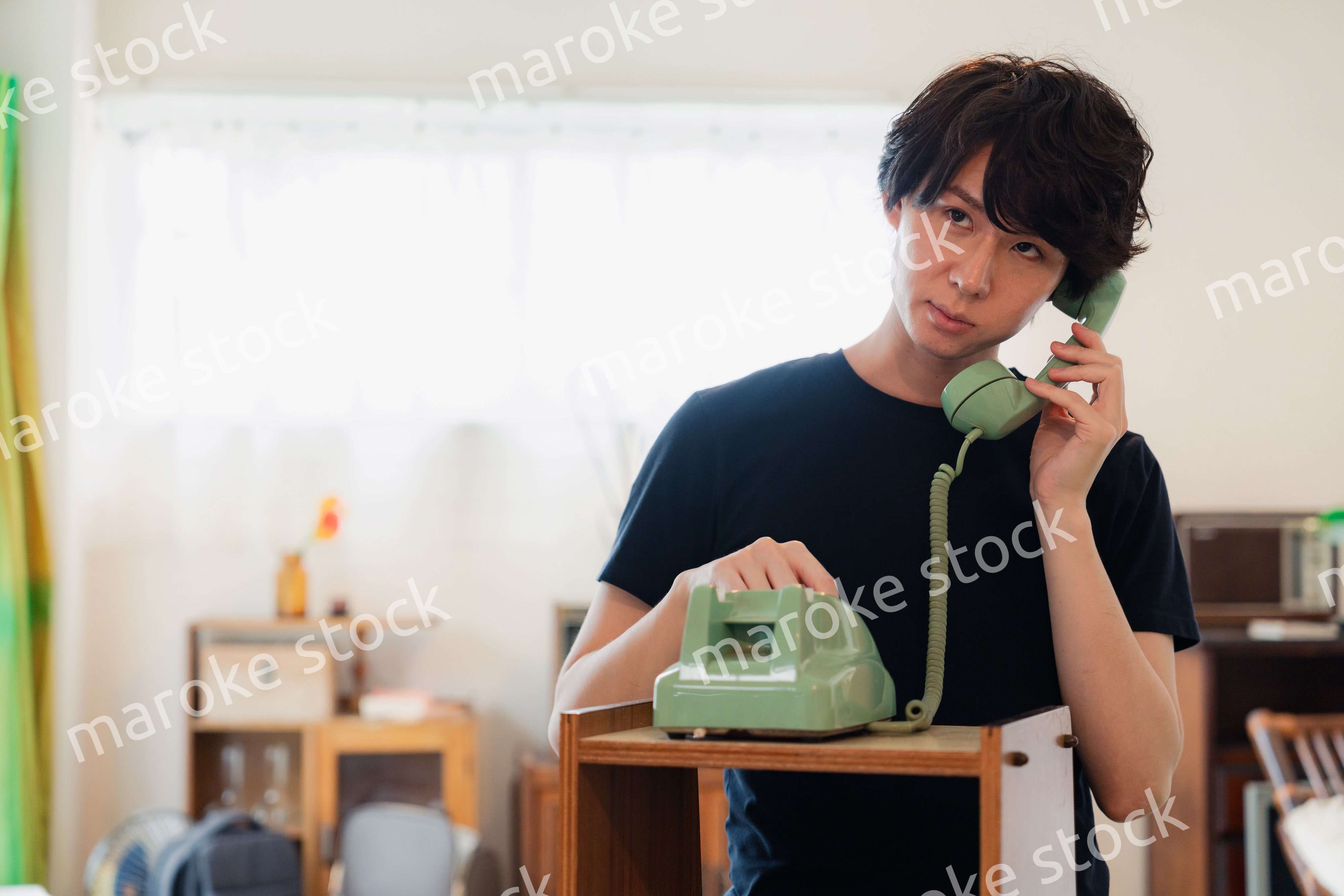 固定電話で電話をする若い男性