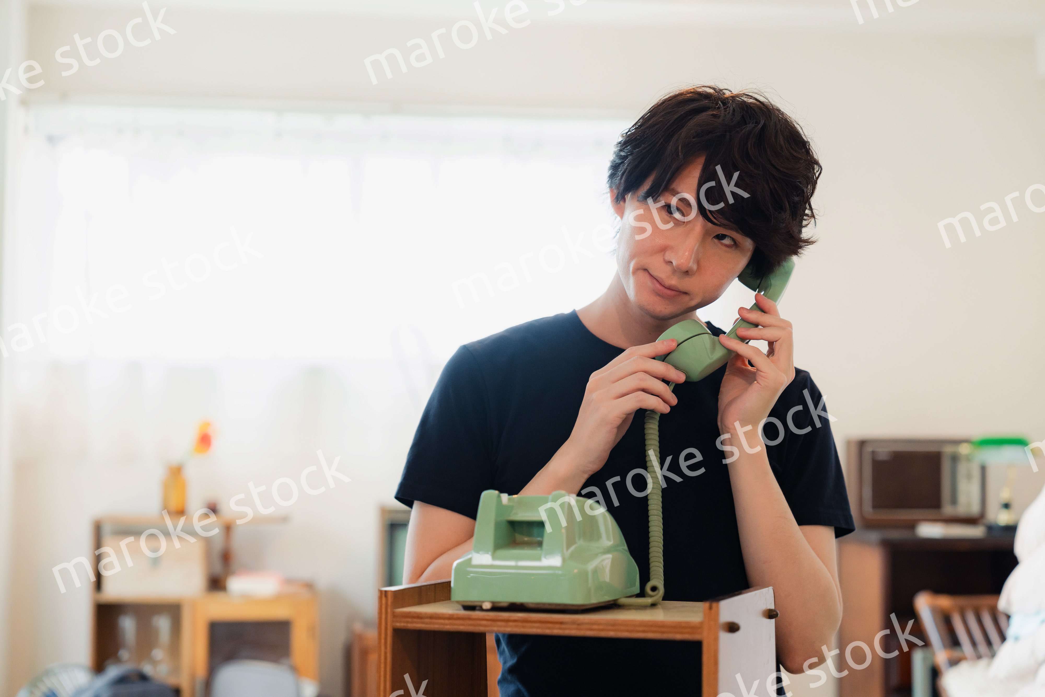 固定電話で電話をする若い男性