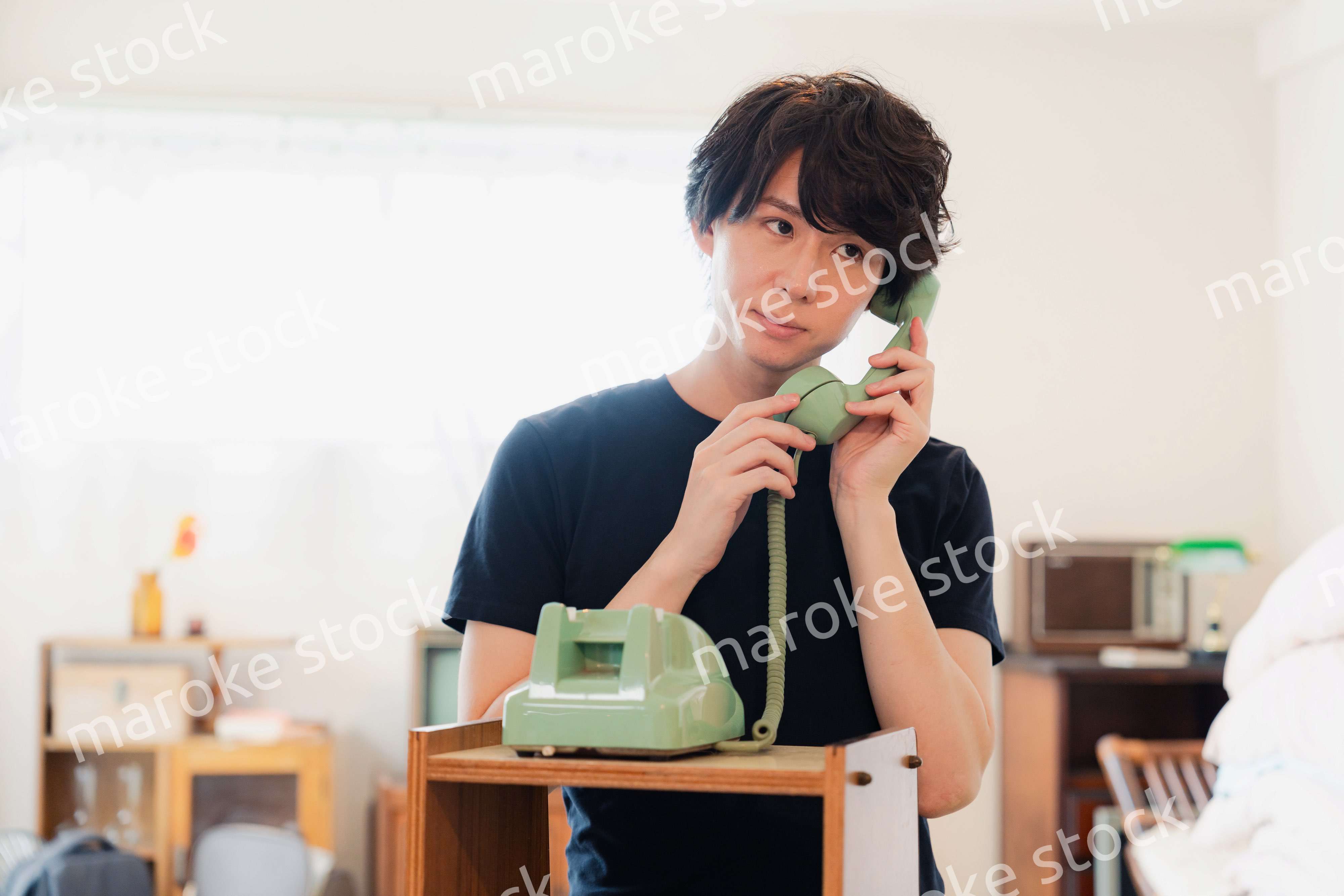 固定電話で電話をする若い男性