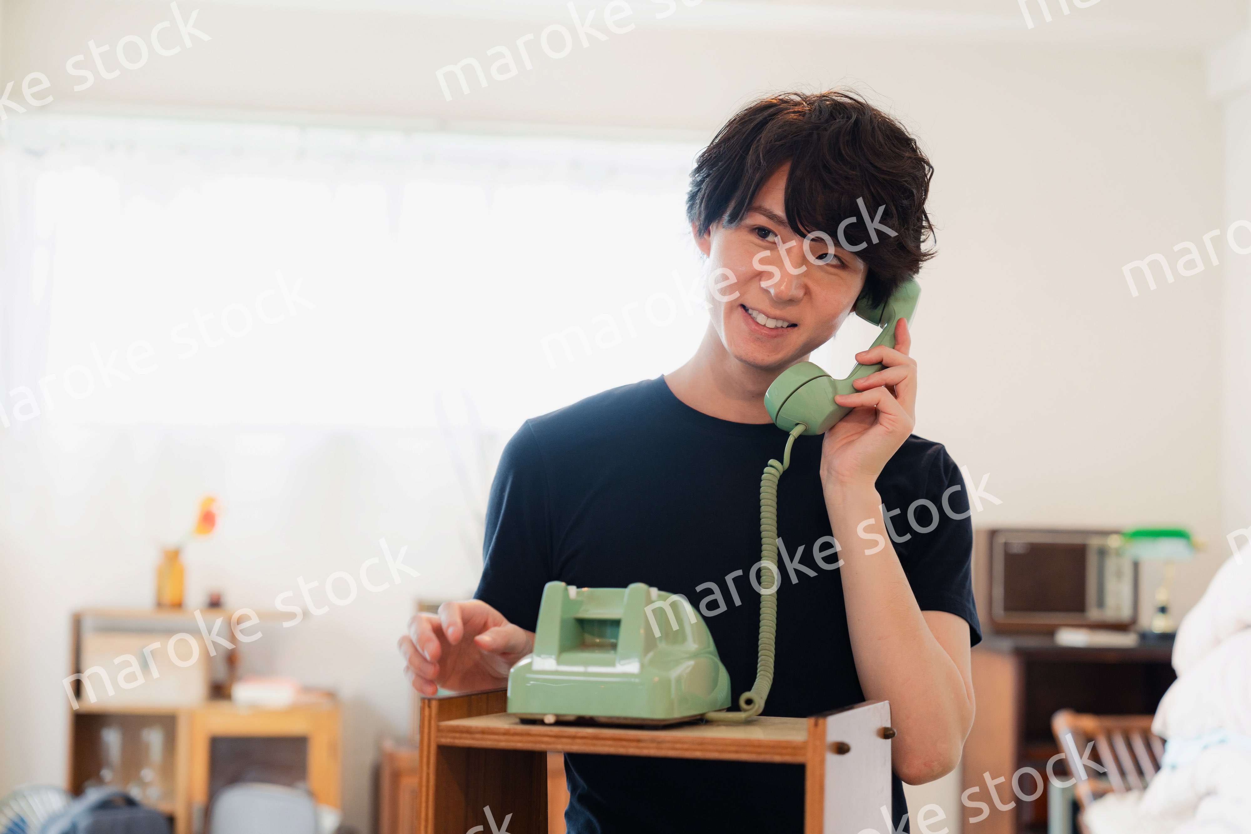固定電話で電話をする若い男性