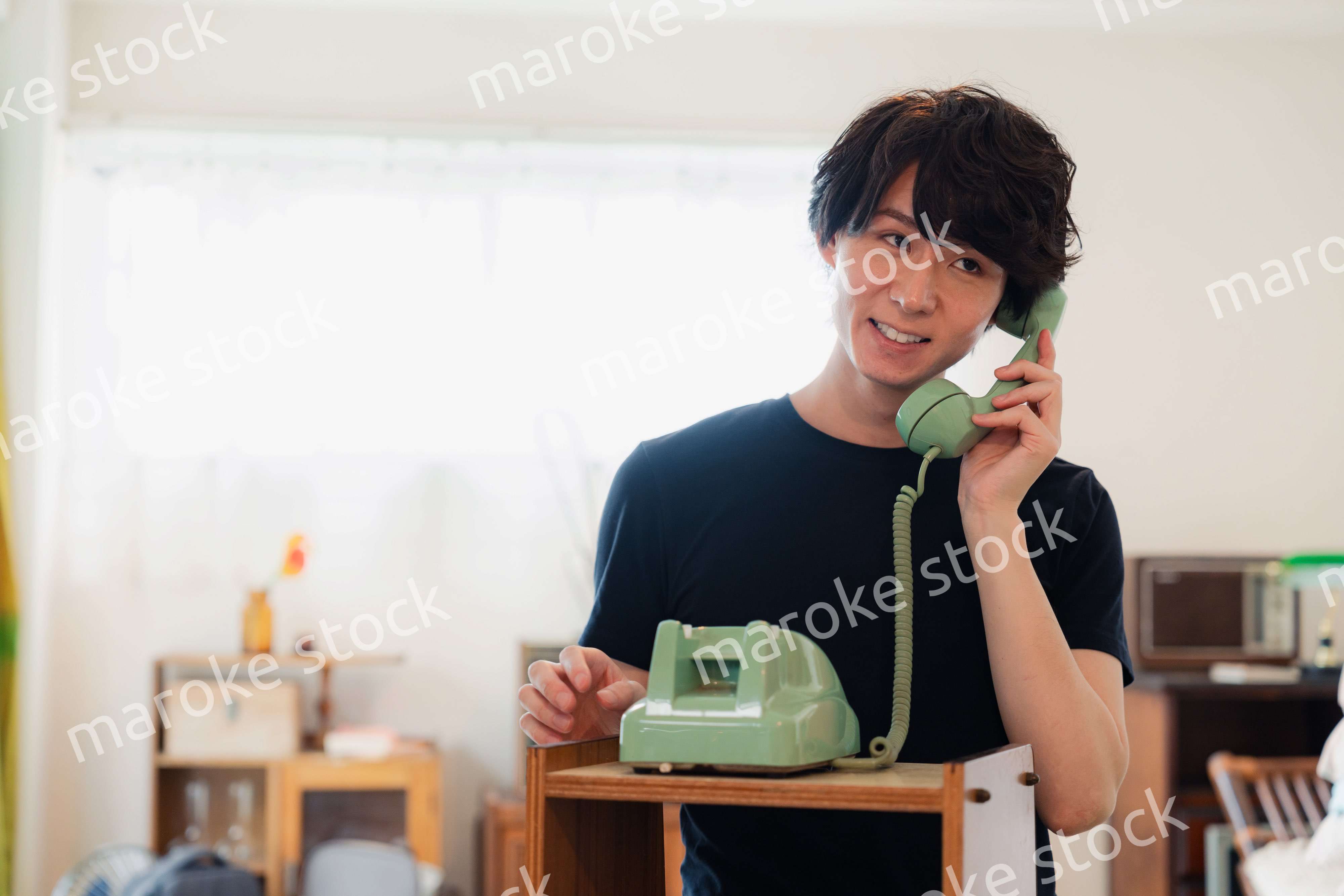 固定電話で電話をする若い男性