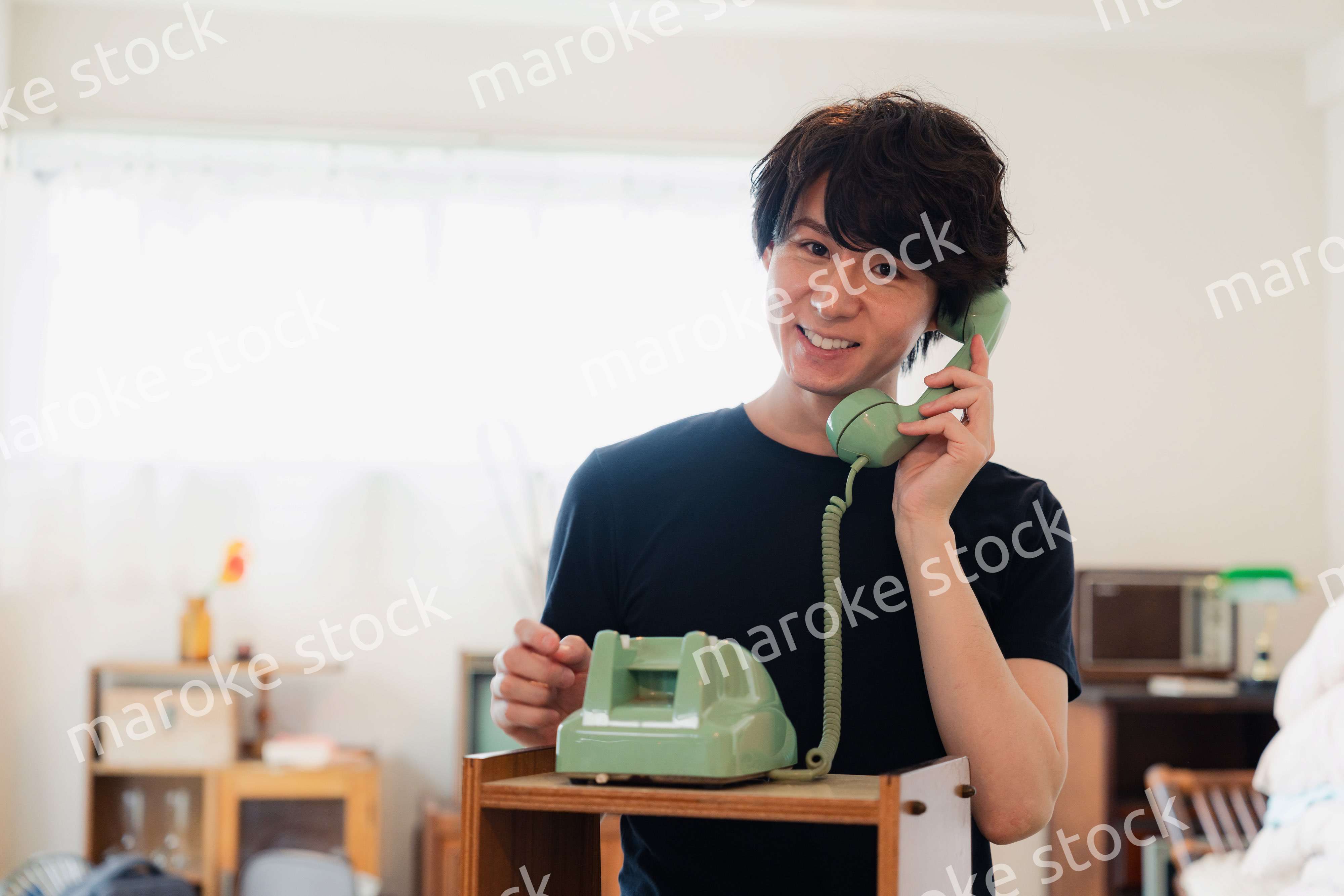 固定電話で電話をする若い男性