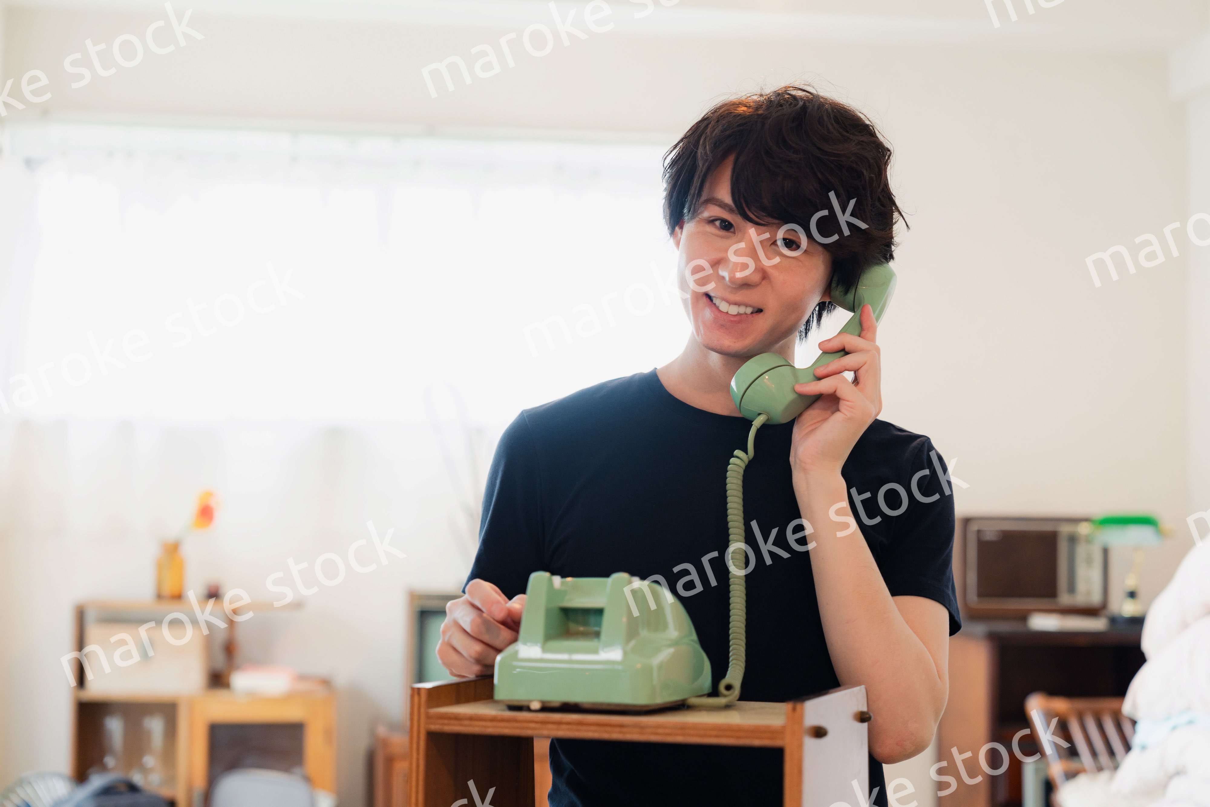 固定電話で電話をする若い男性