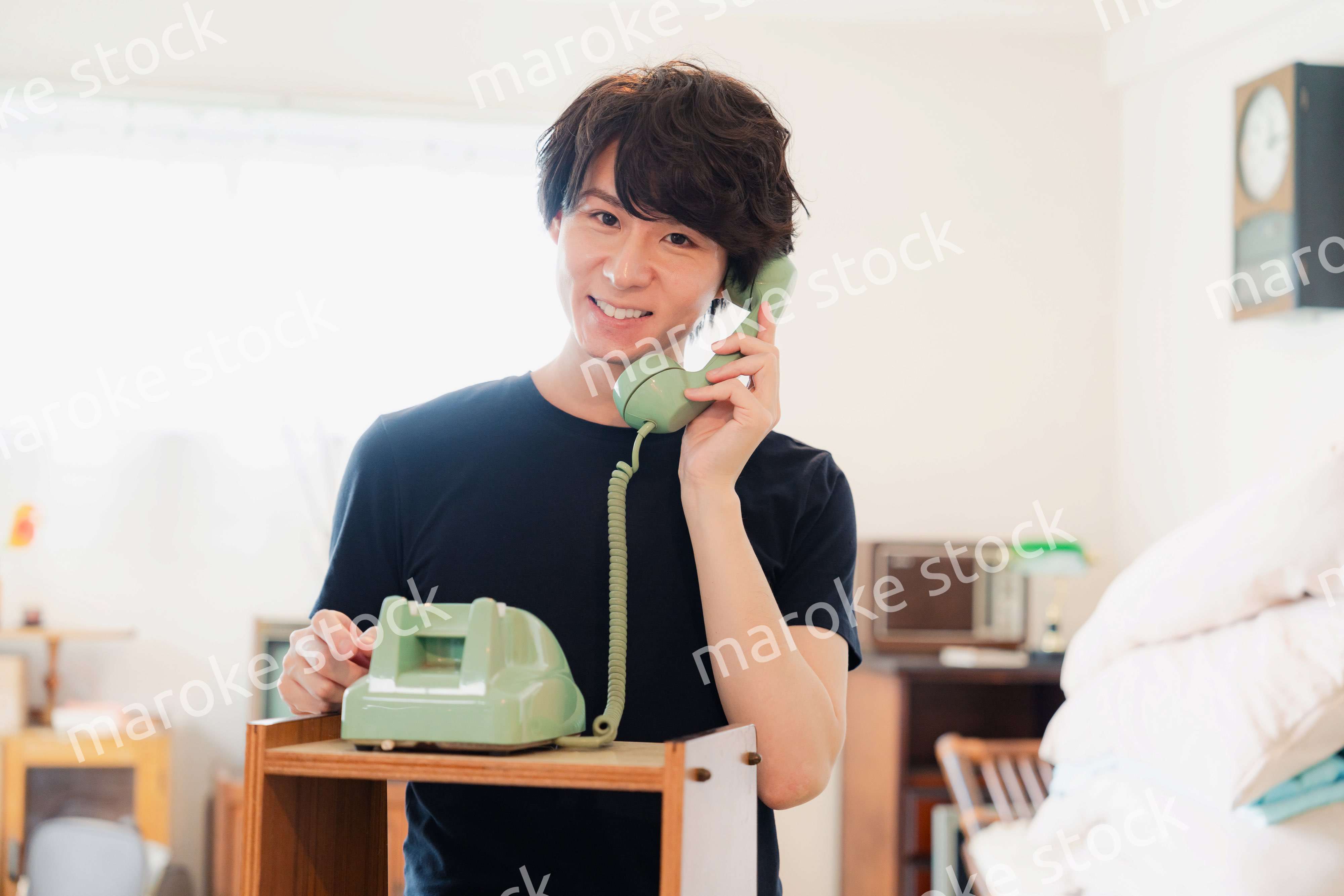 固定電話で電話をする若い男性