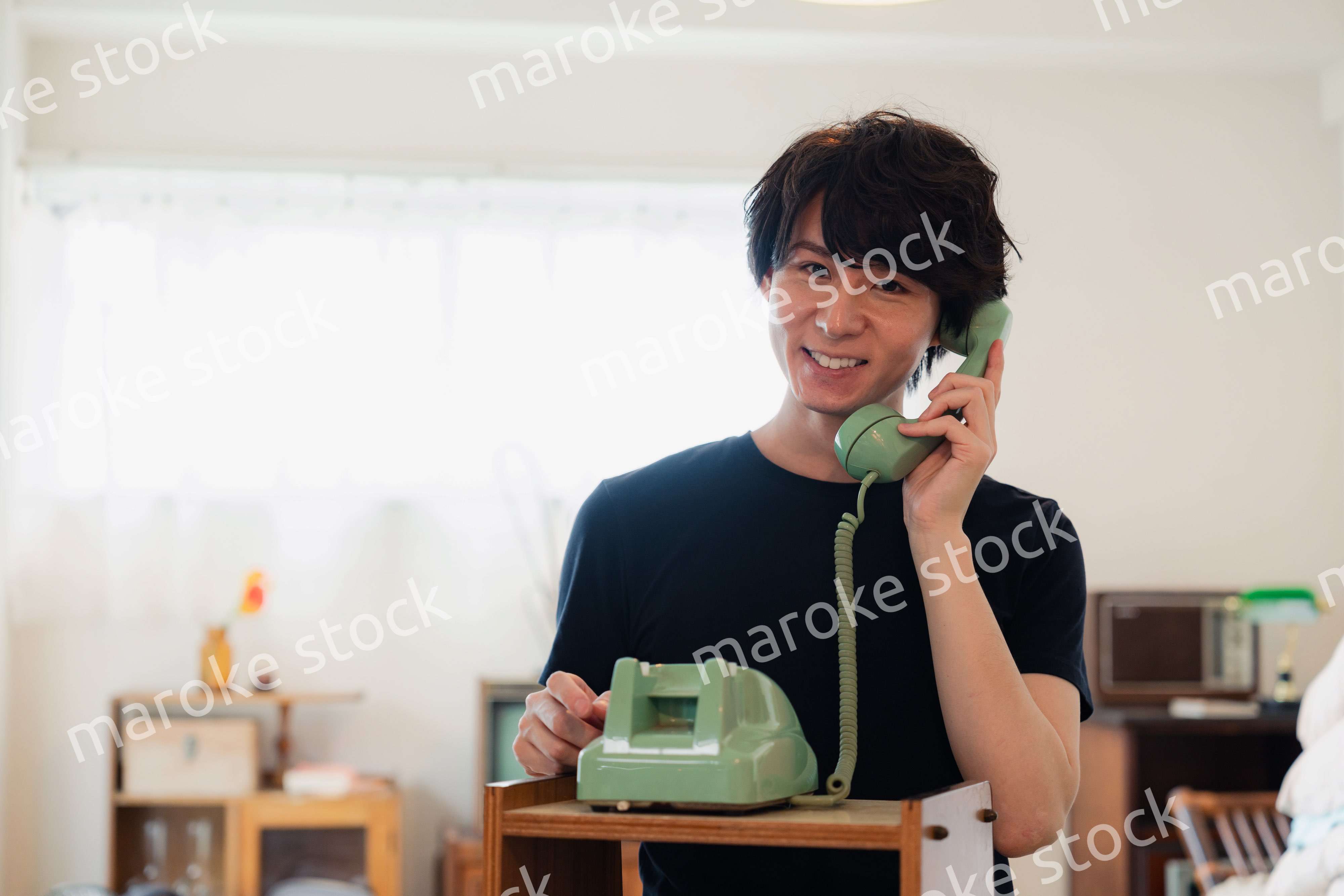 固定電話で電話をする若い男性