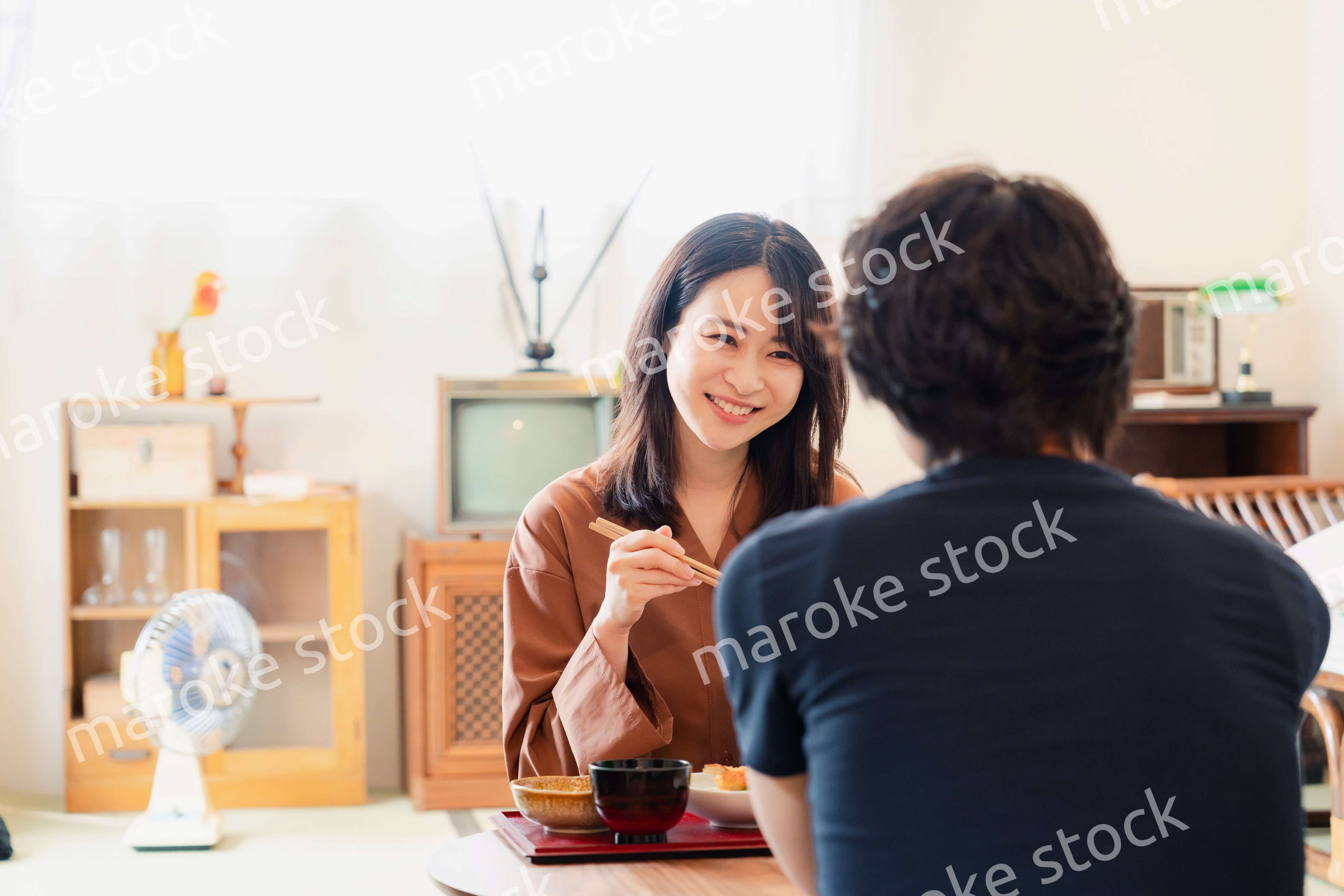 ドラマのようなレトロな雰囲気の食卓でごはんを食べる若い夫婦