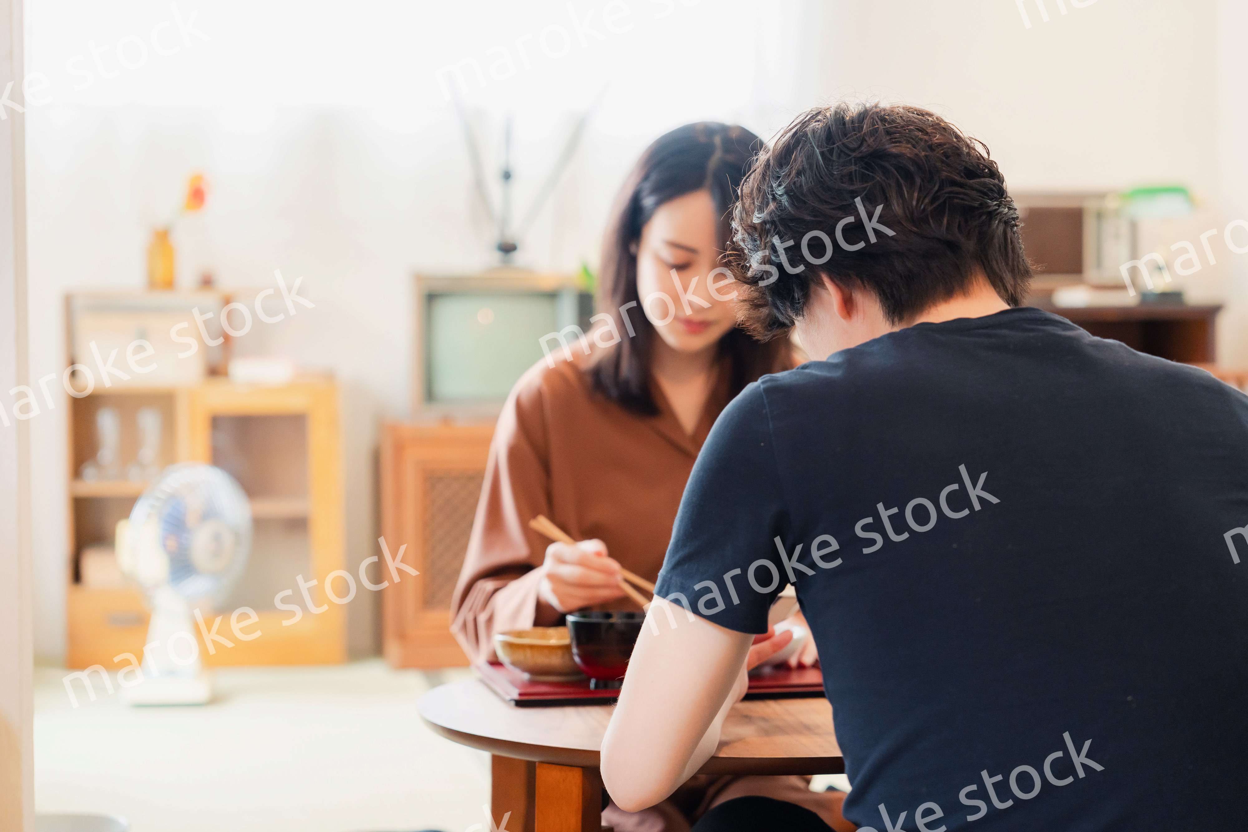 ドラマのようなレトロな雰囲気の食卓でごはんを食べる若い夫婦