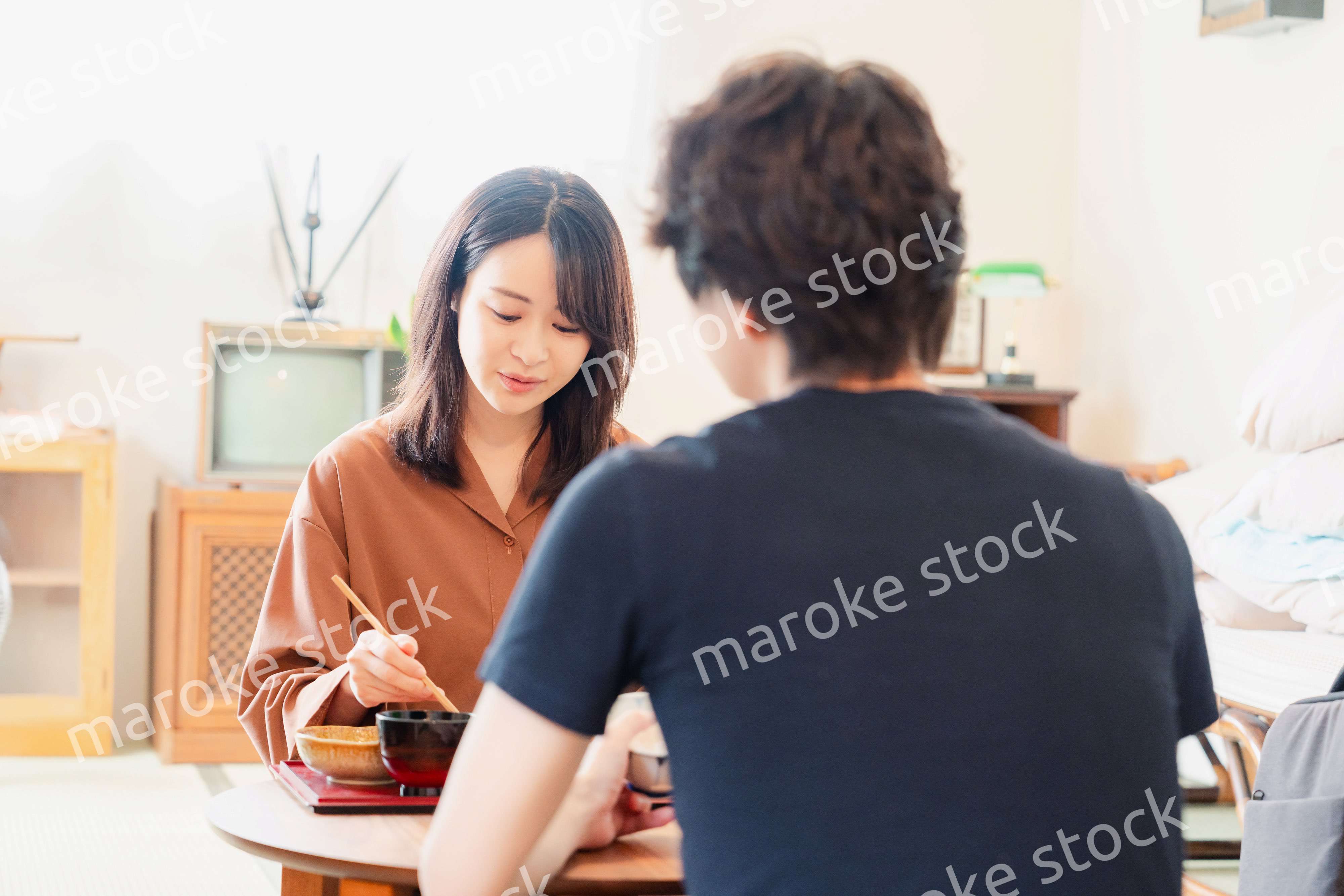 ドラマのようなレトロな雰囲気の食卓でごはんを食べる若い夫婦