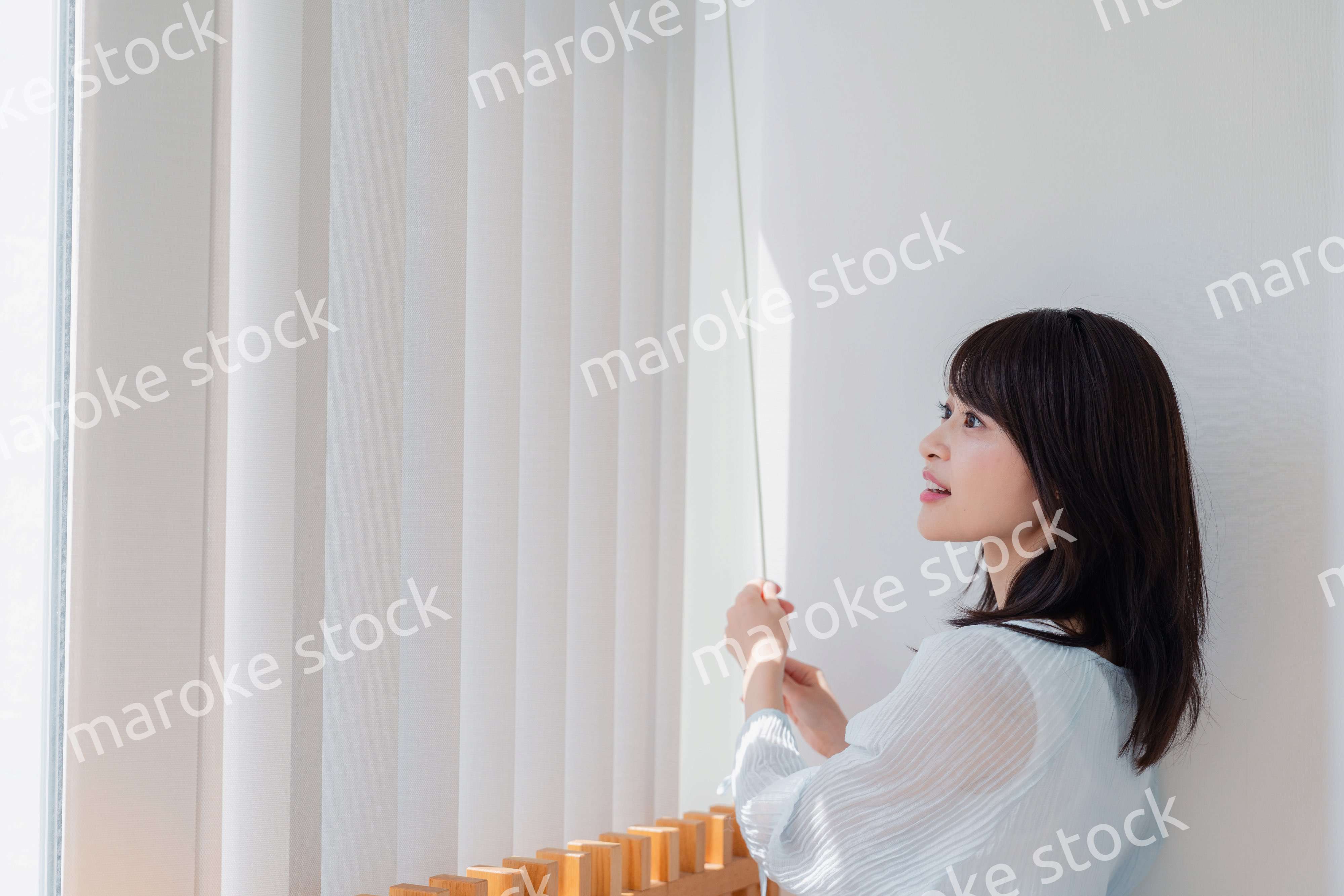 バーチカルブラインドを使う若い女性