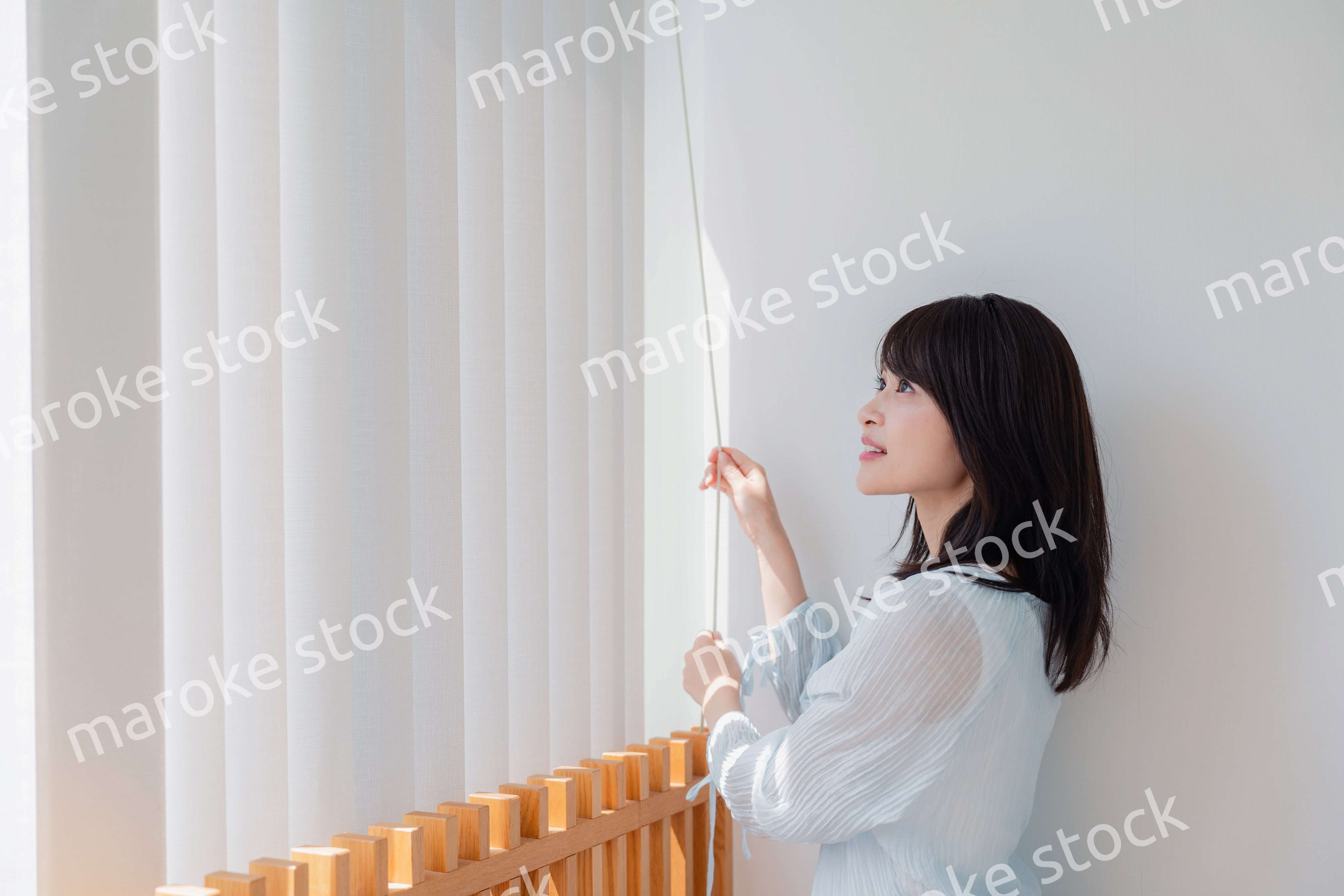 バーチカルブラインドを使う若い女性