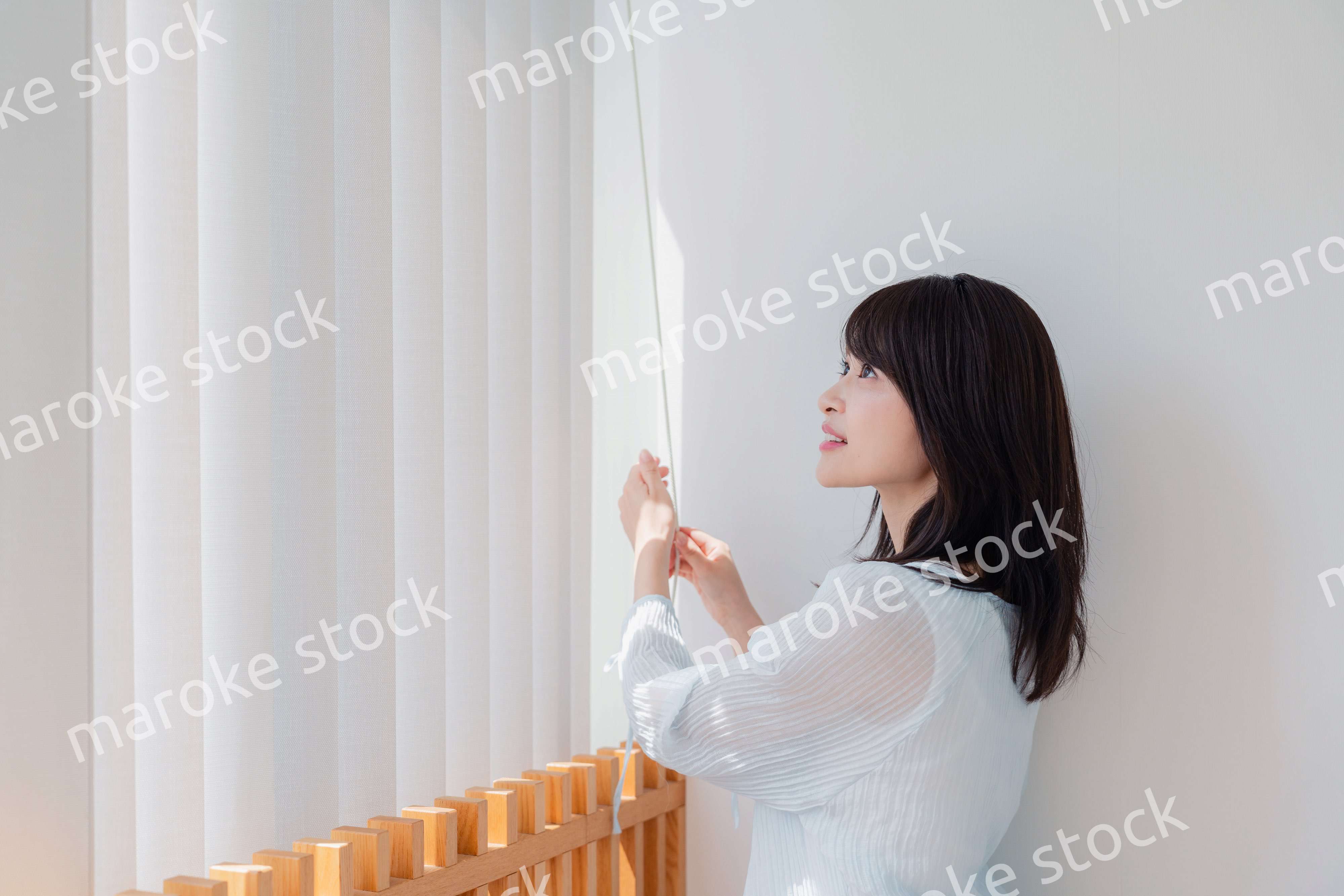 バーチカルブラインドを使う若い女性