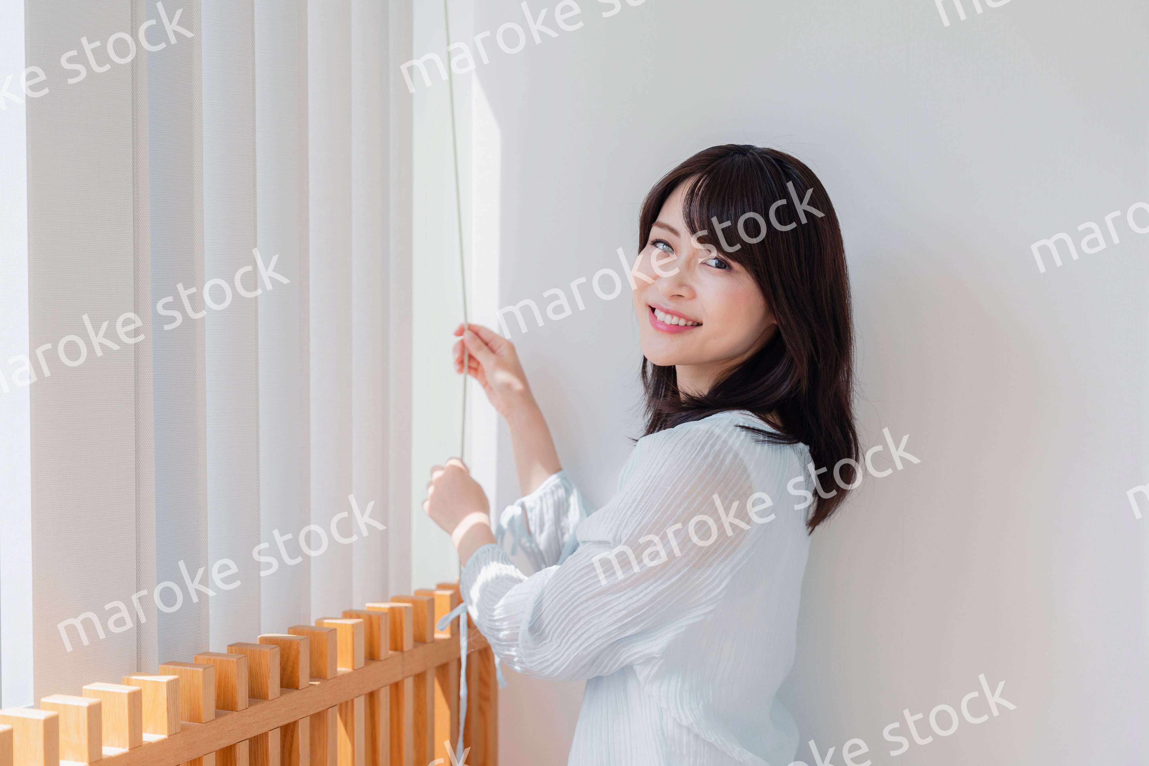 バーチカルブラインドを使う若い女性