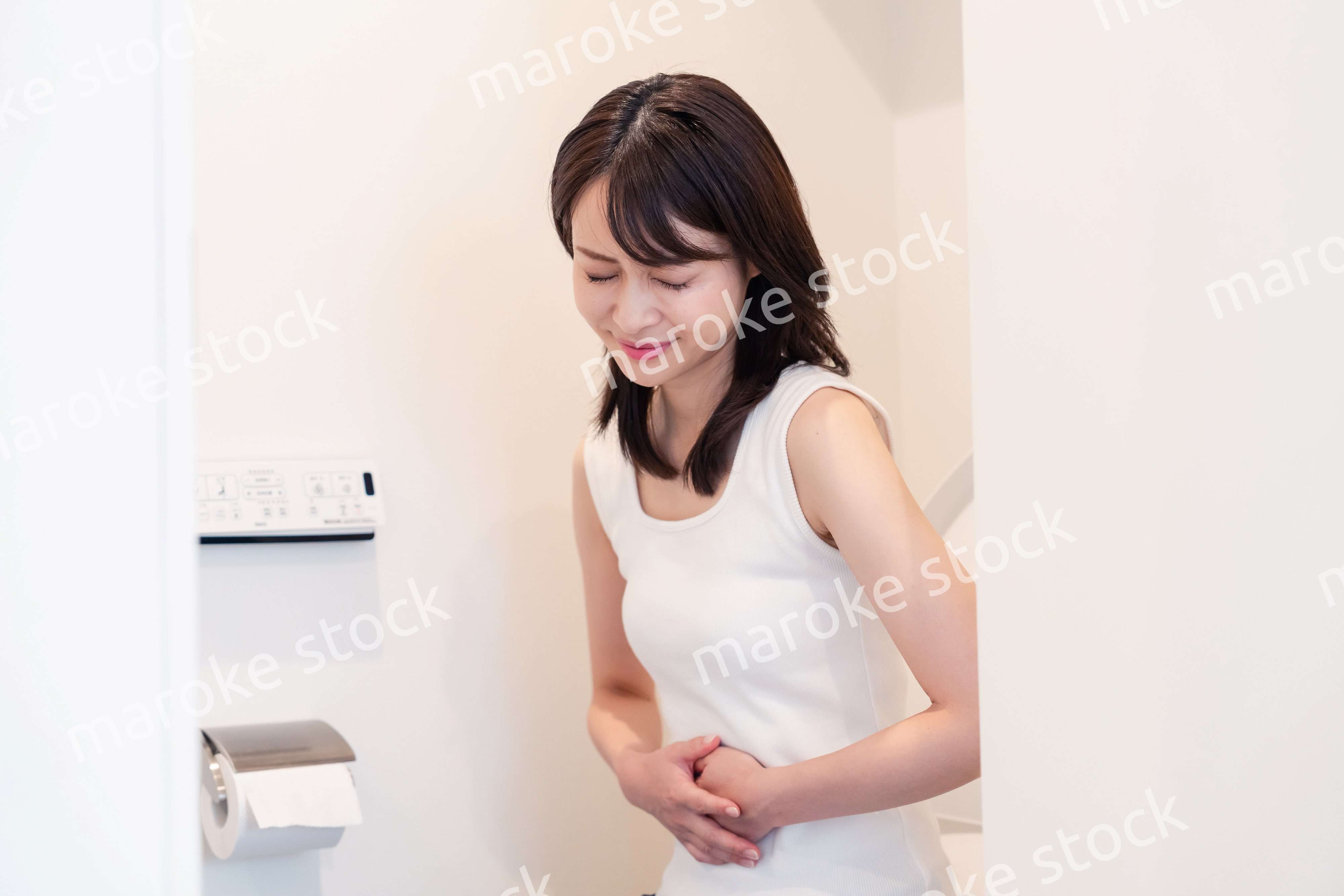 トイレでひどい腹痛に苦しむ若い女性
