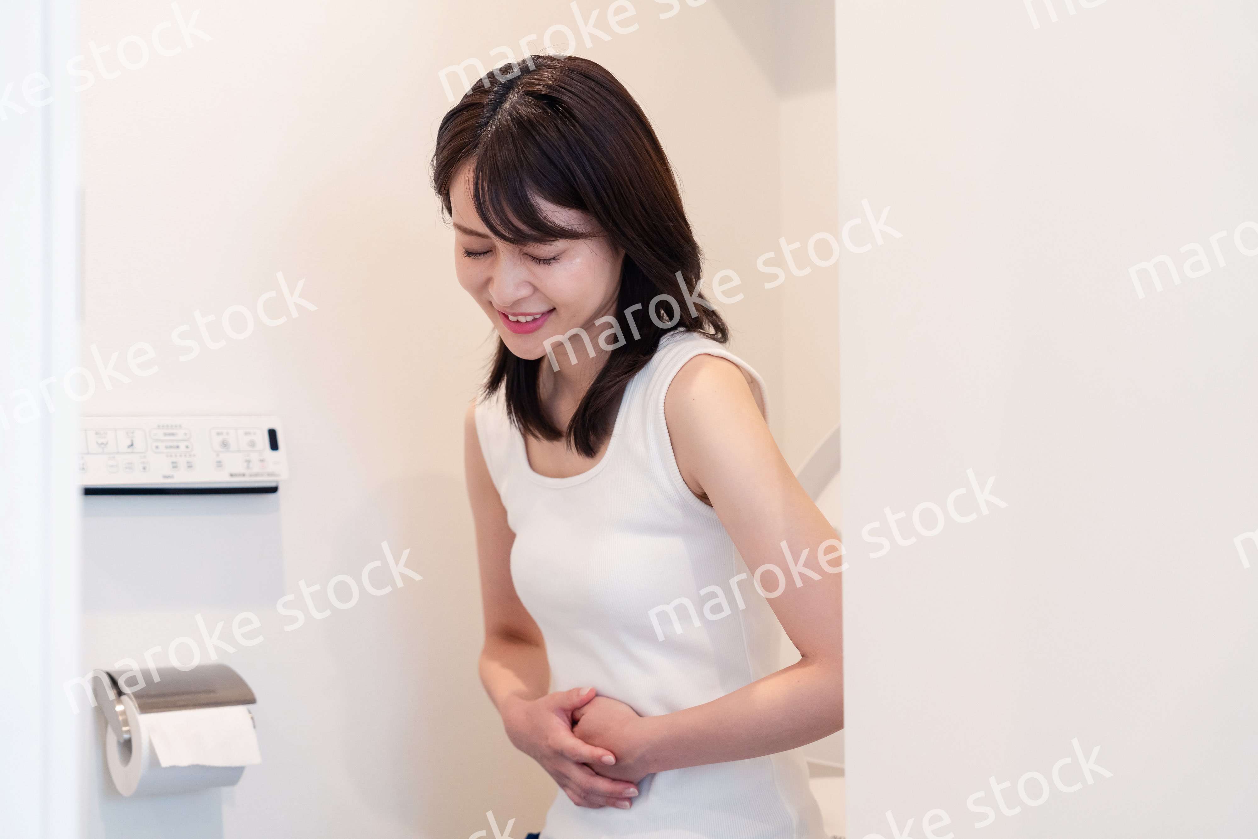 トイレでひどい腹痛に苦しむ若い女性