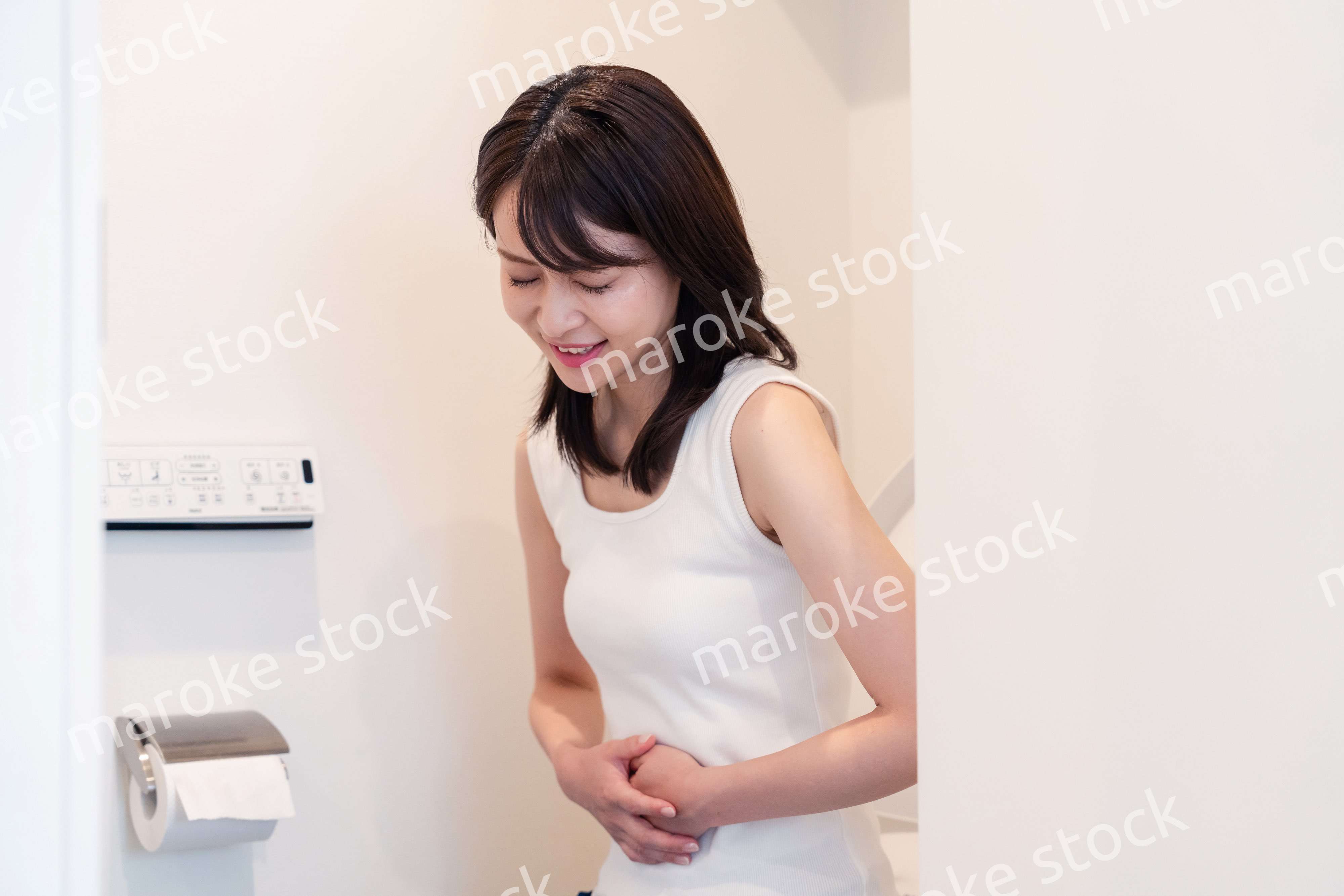 トイレでひどい腹痛に苦しむ若い女性