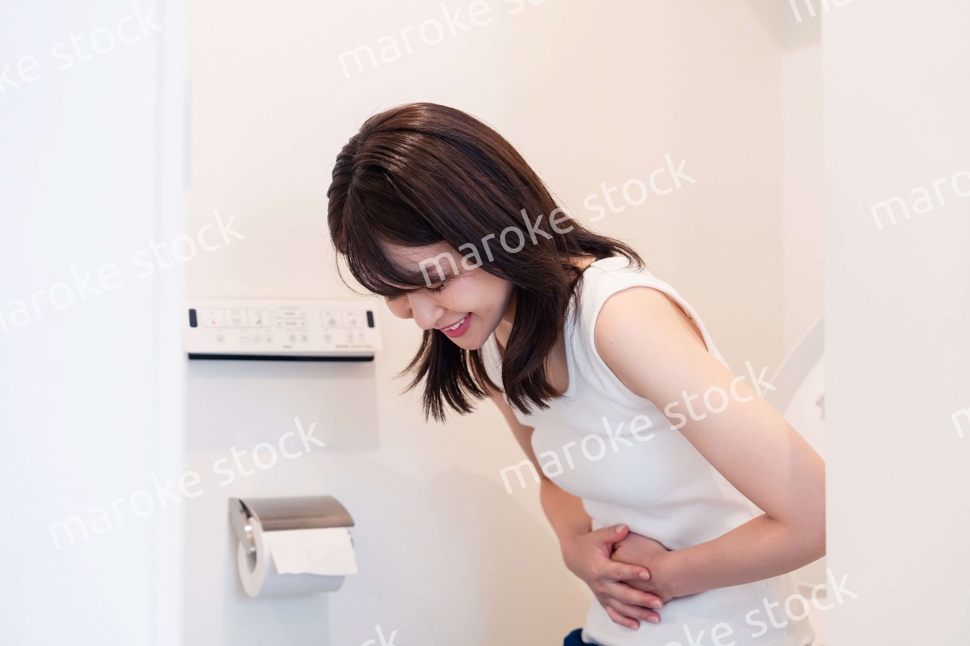 トイレでひどい腹痛に苦しむ若い女性