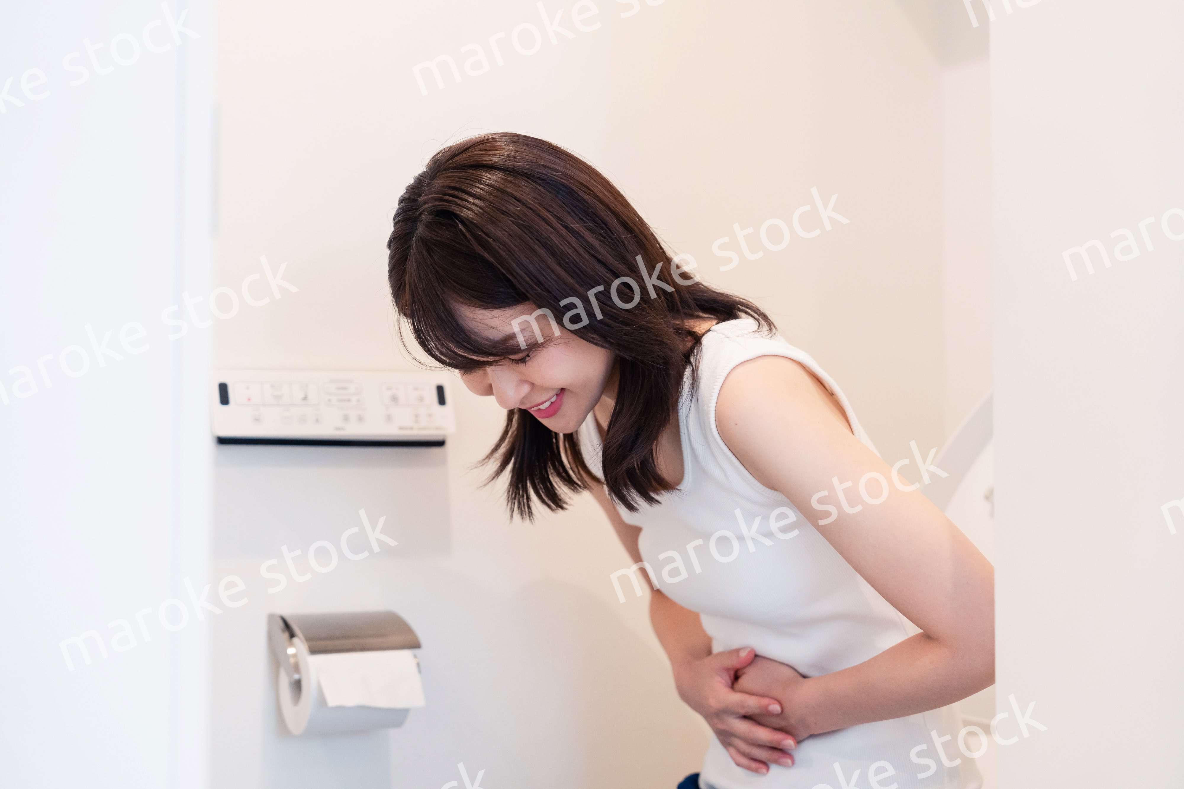 トイレでひどい腹痛に苦しむ若い女性
