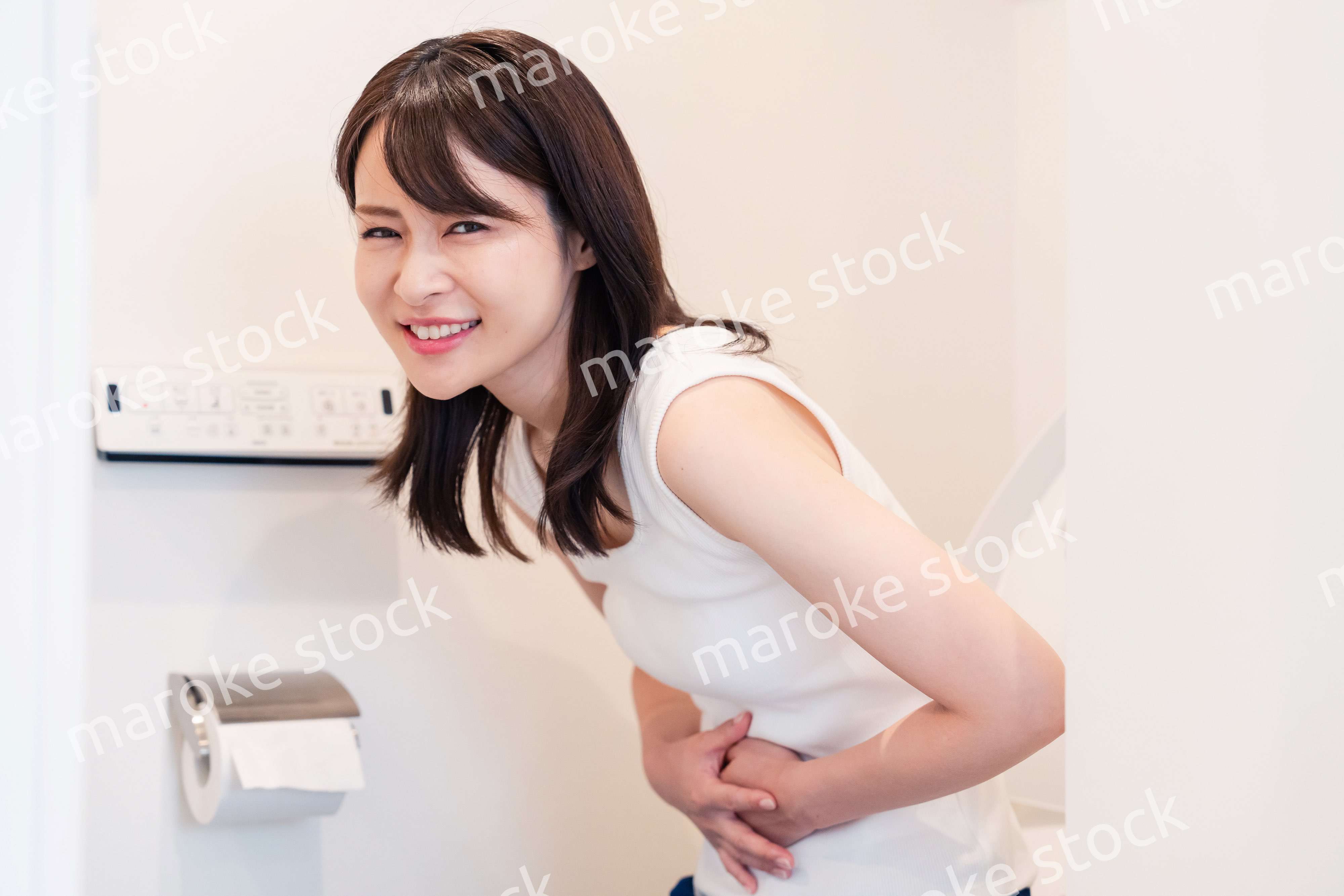 トイレでひどい腹痛に苦しむ若い女性
