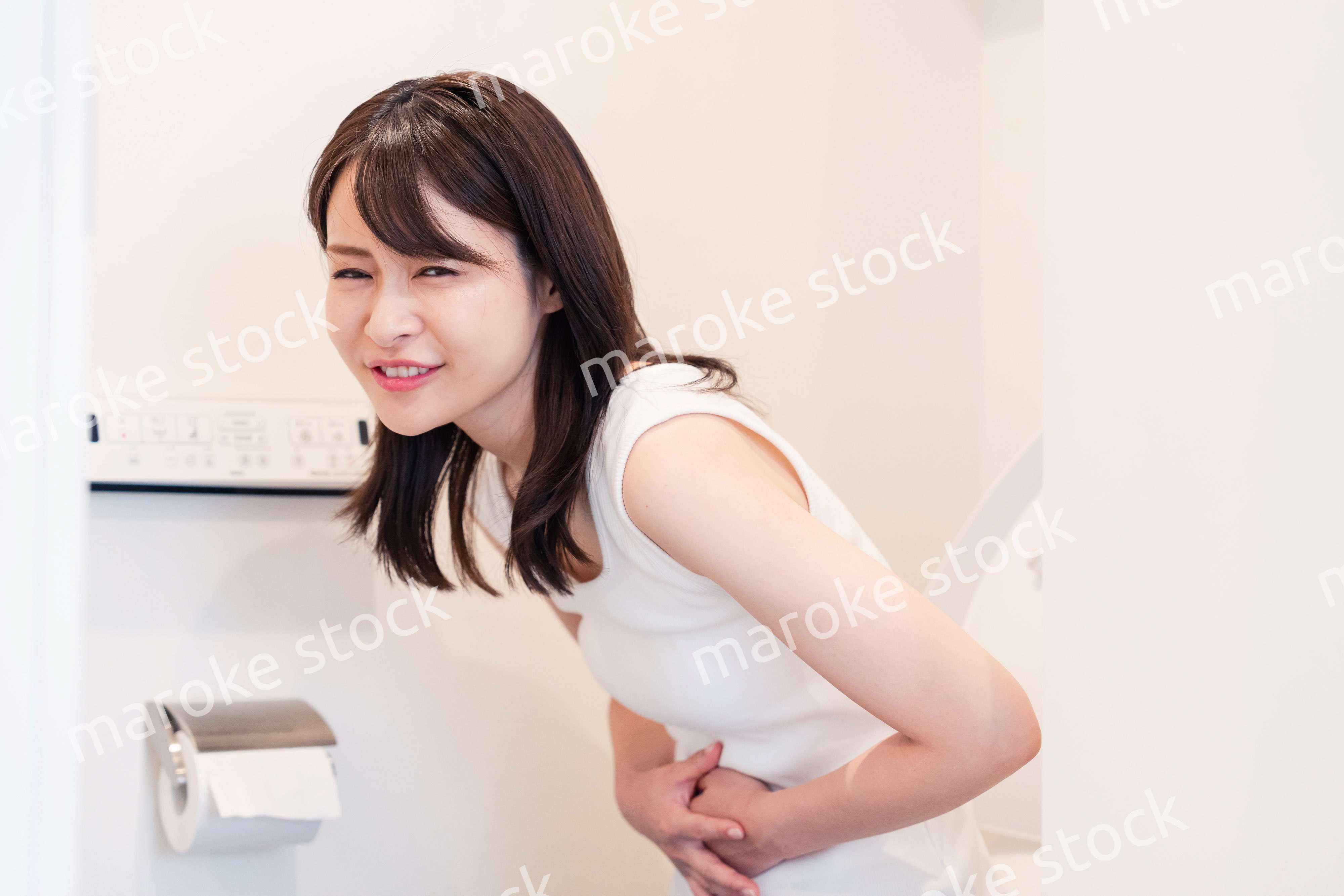トイレでひどい腹痛に苦しむ若い女性