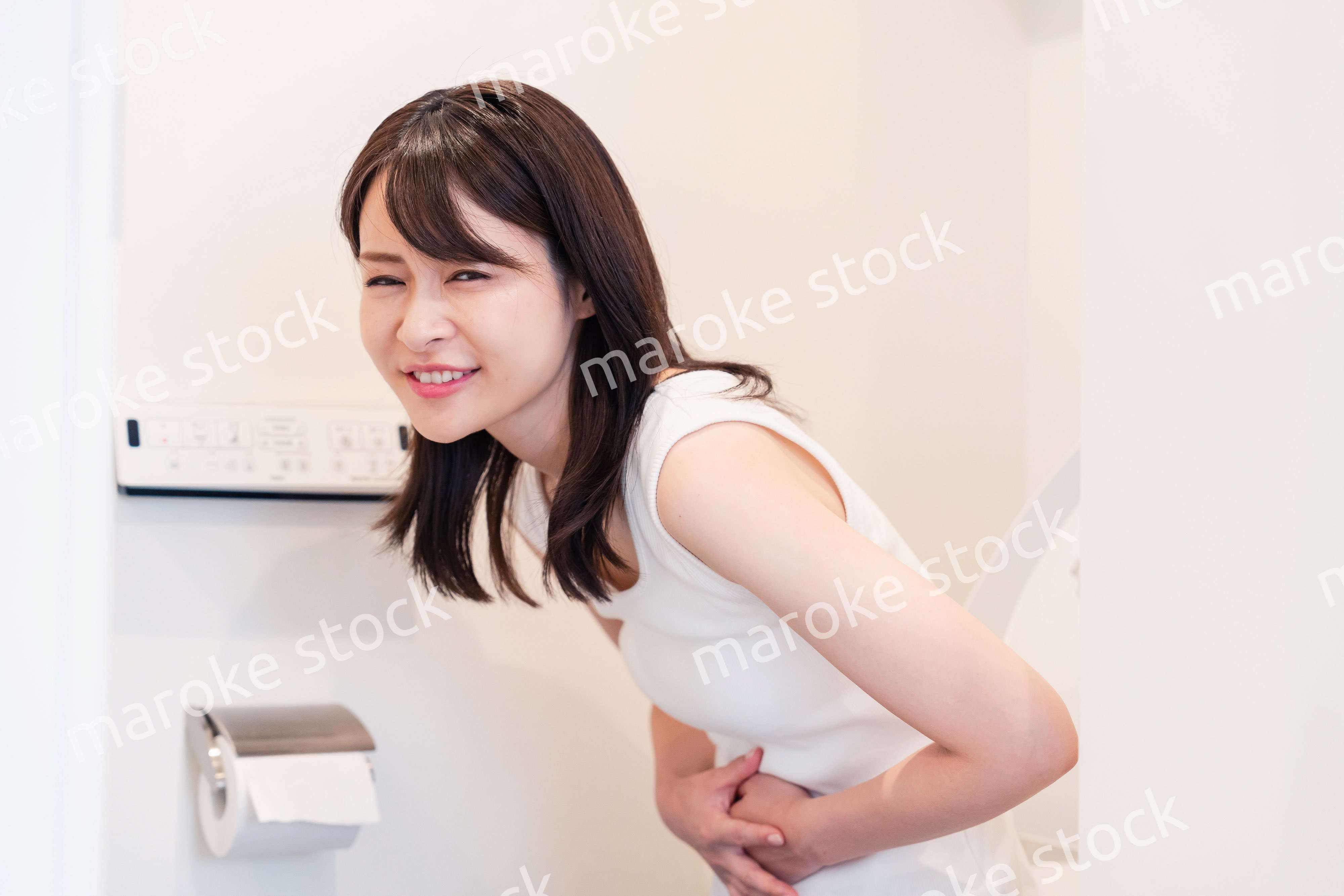 トイレでひどい腹痛に苦しむ若い女性