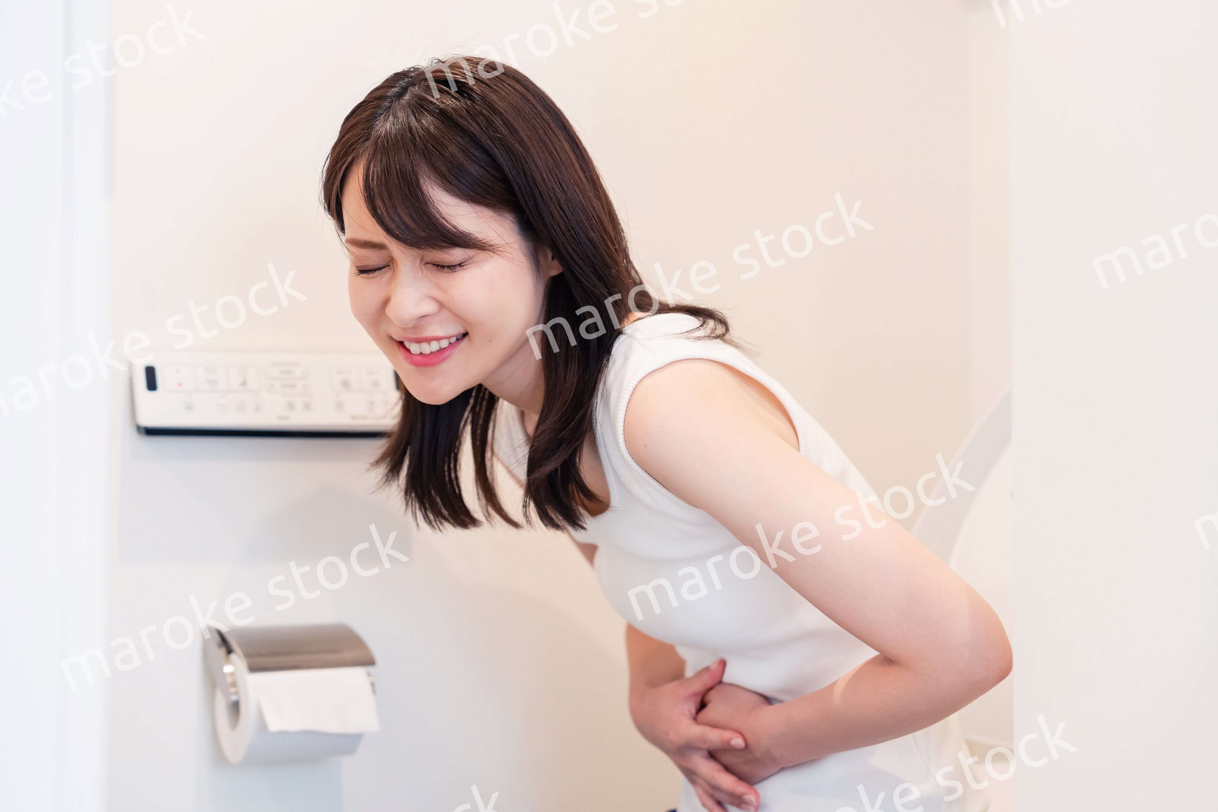 トイレでひどい腹痛に苦しむ若い女性