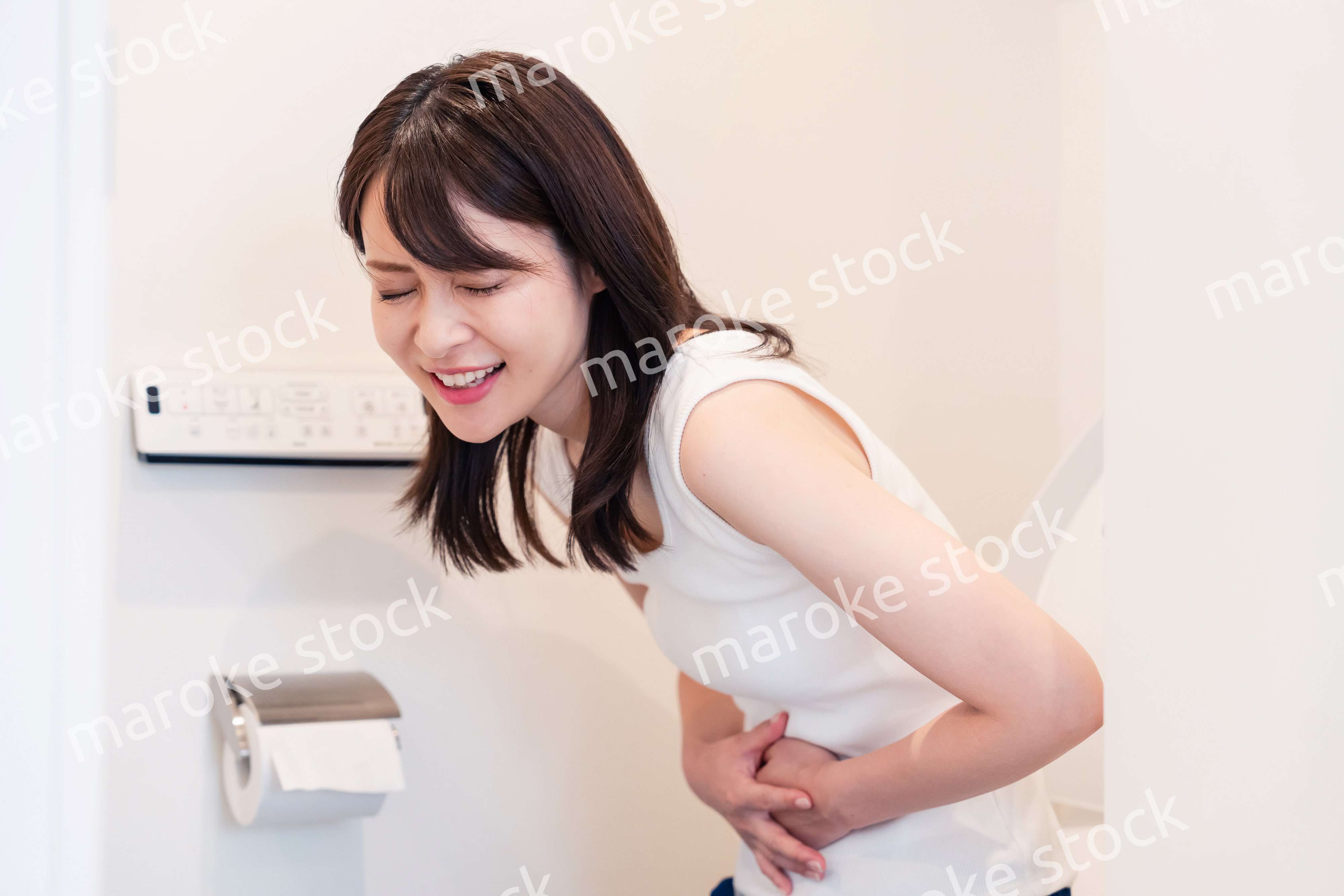 トイレでひどい腹痛に苦しむ若い女性