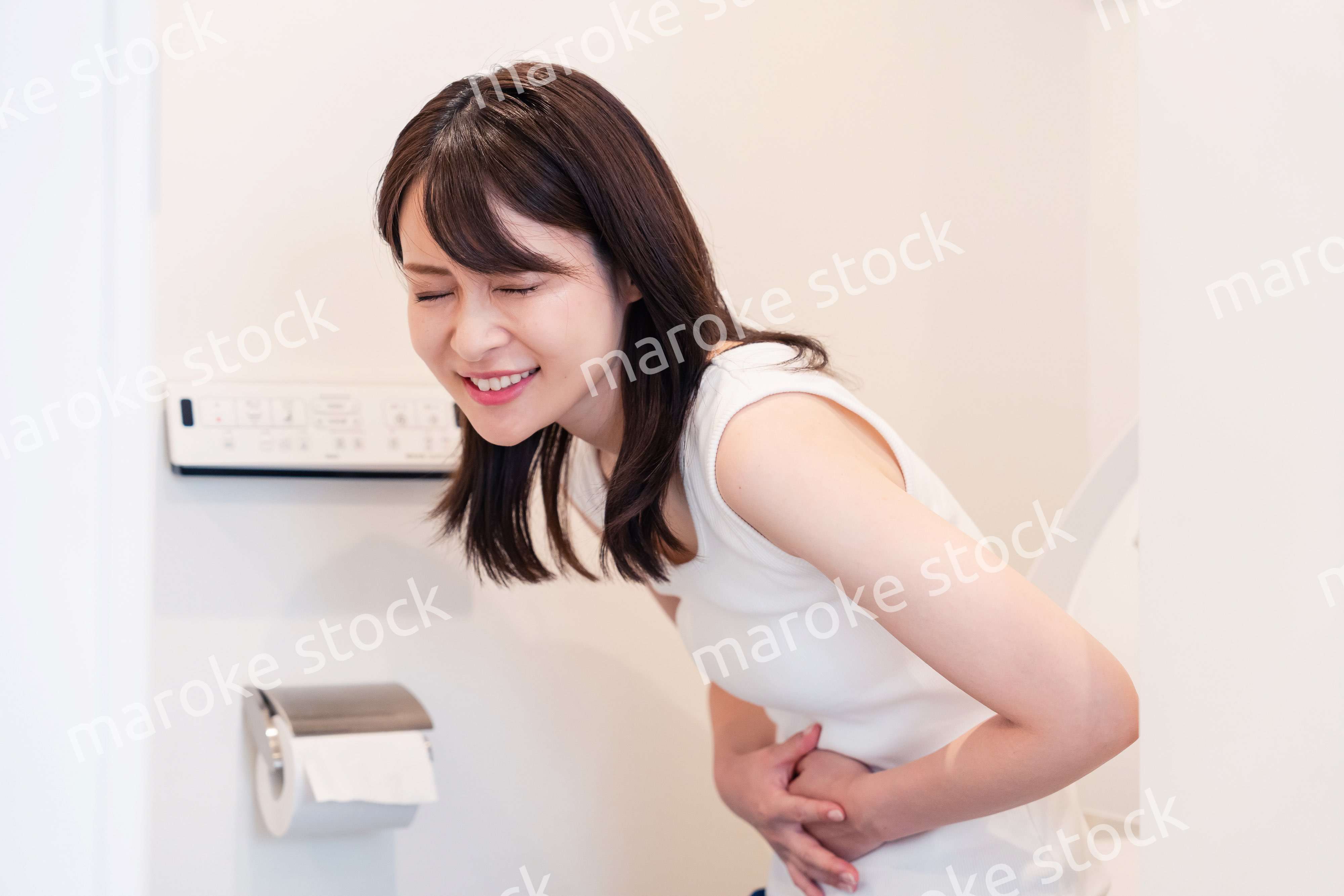 トイレでひどい腹痛に苦しむ若い女性