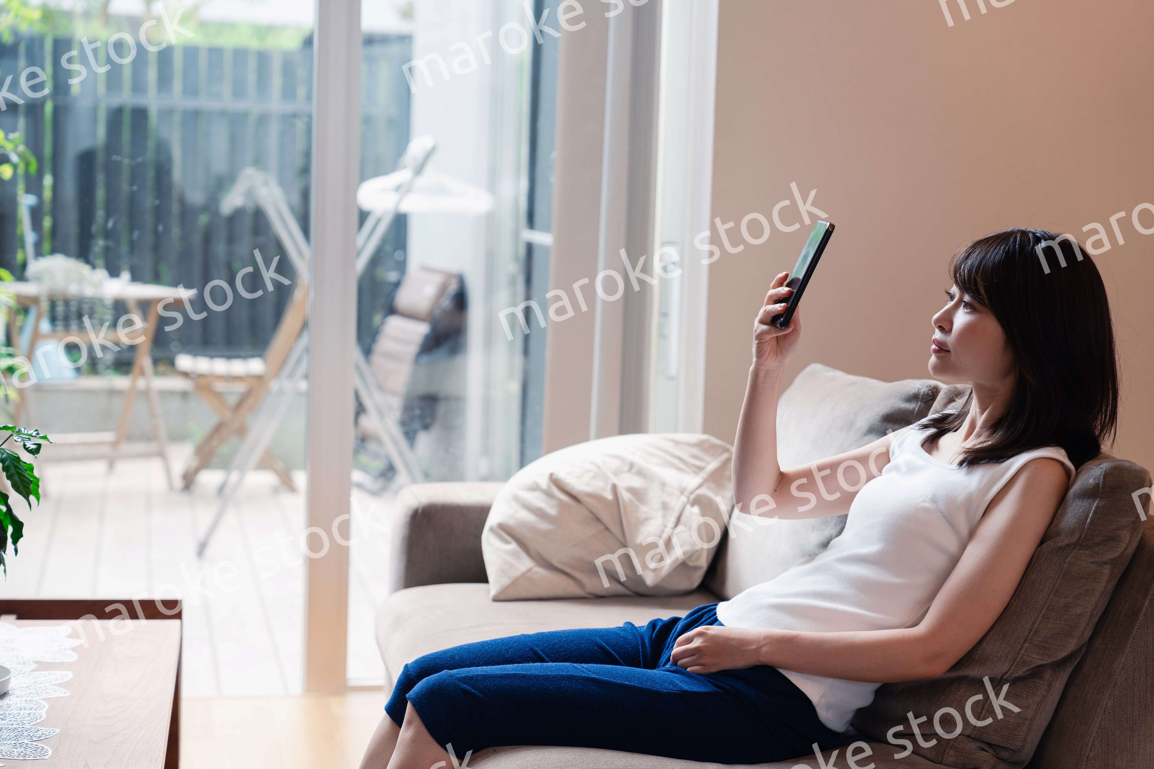 ソファでリラックスしてスマホを使う若い女性