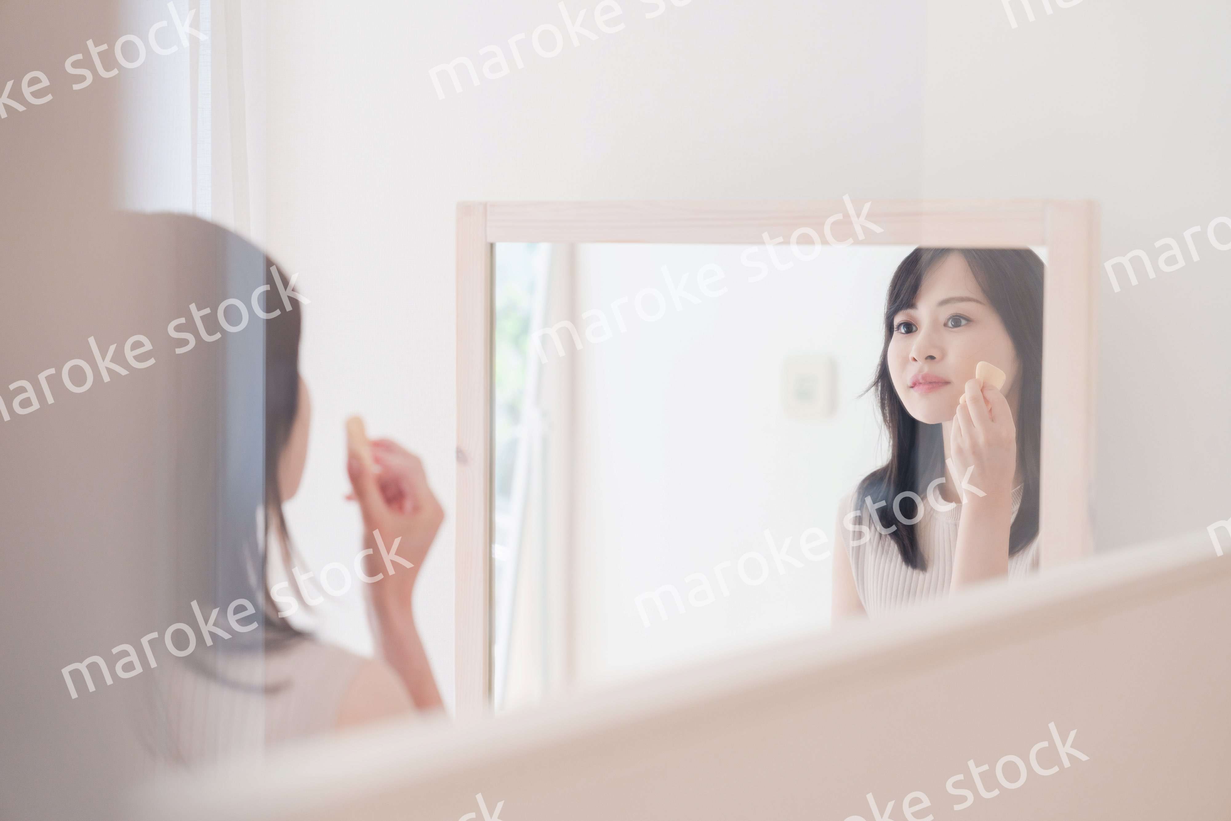 家でメイクをする若い女性