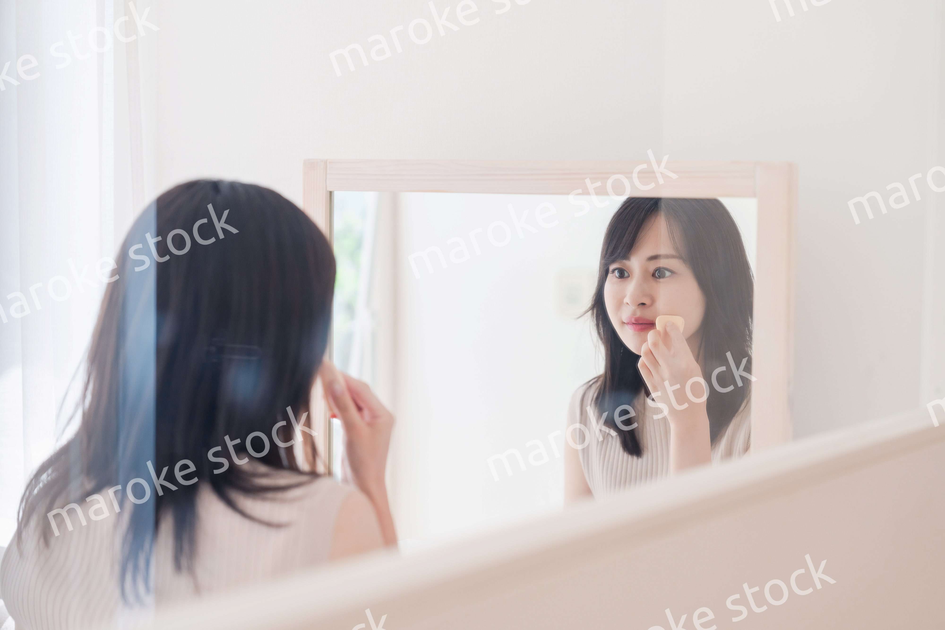 家でメイクをする若い女性