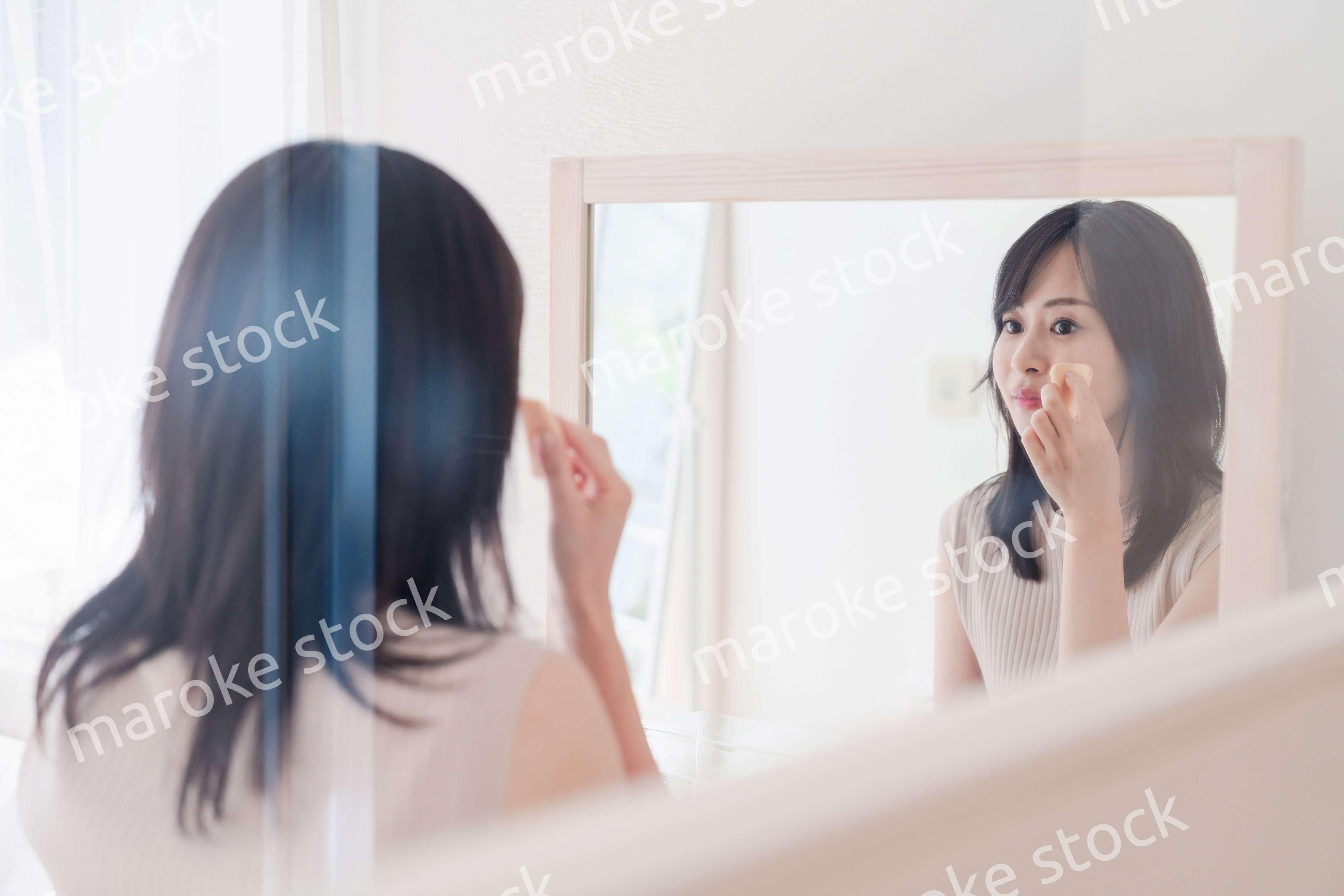 家でメイクをする若い女性