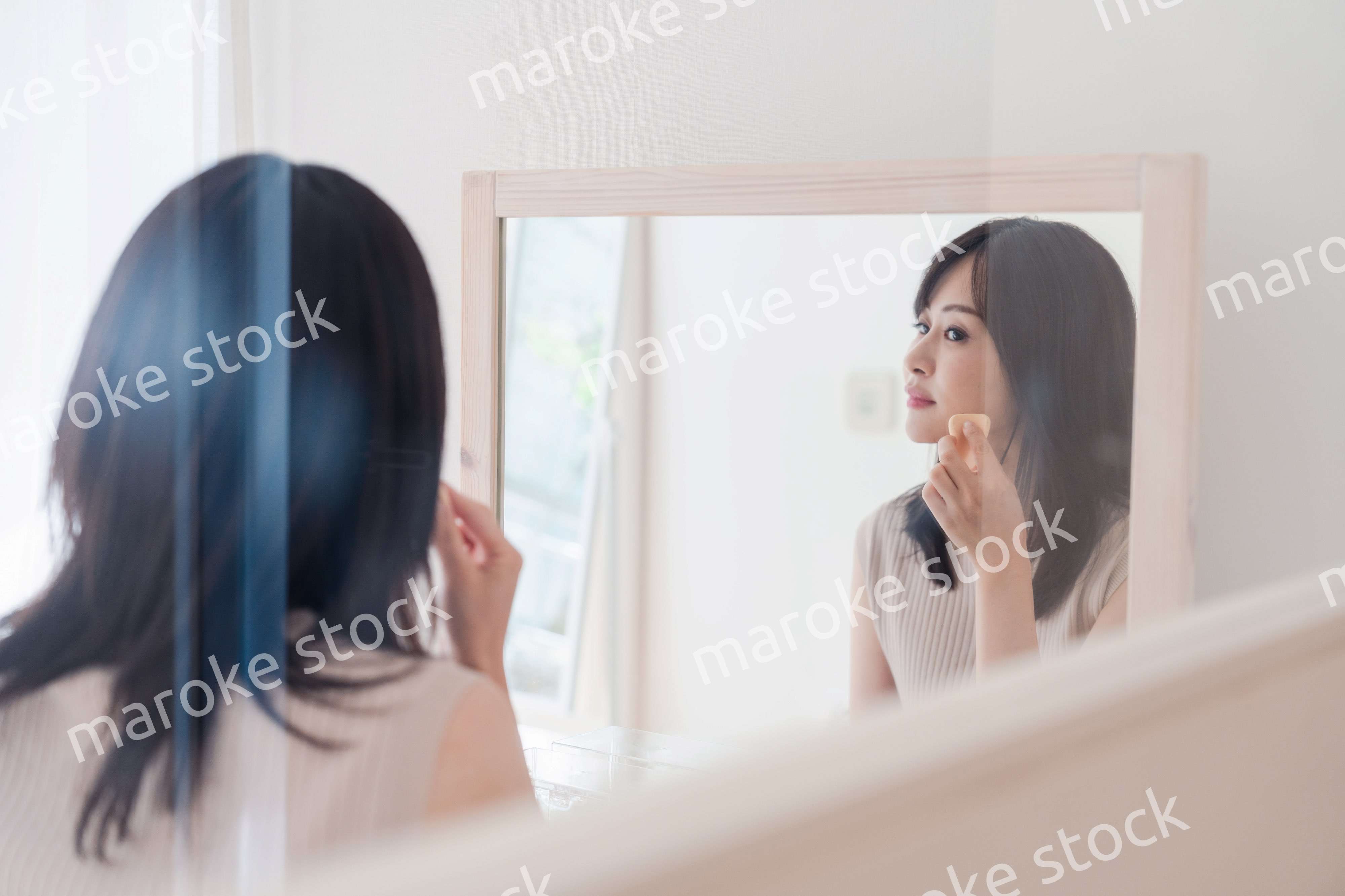 家でメイクをする若い女性