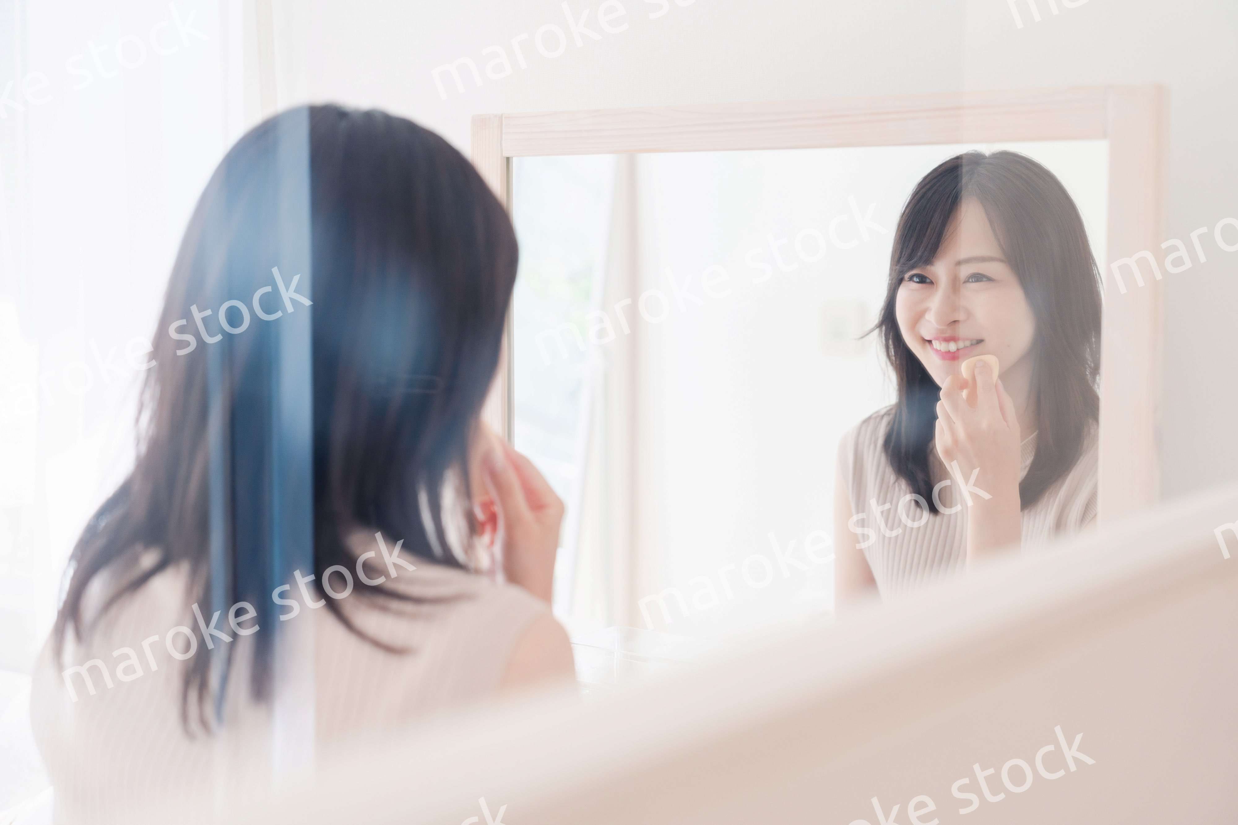 家でメイクをする若い女性