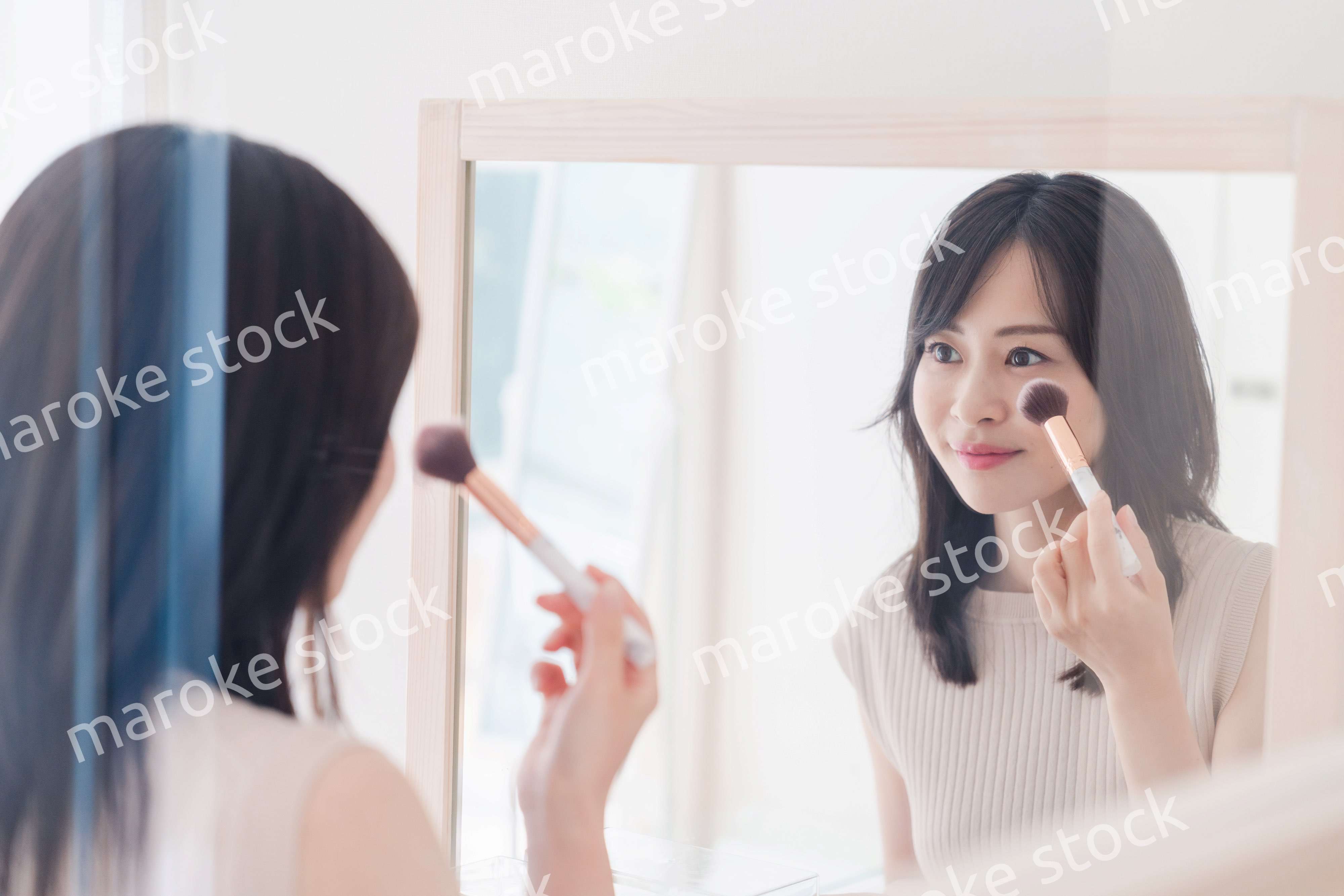 家でメイクをする若い女性