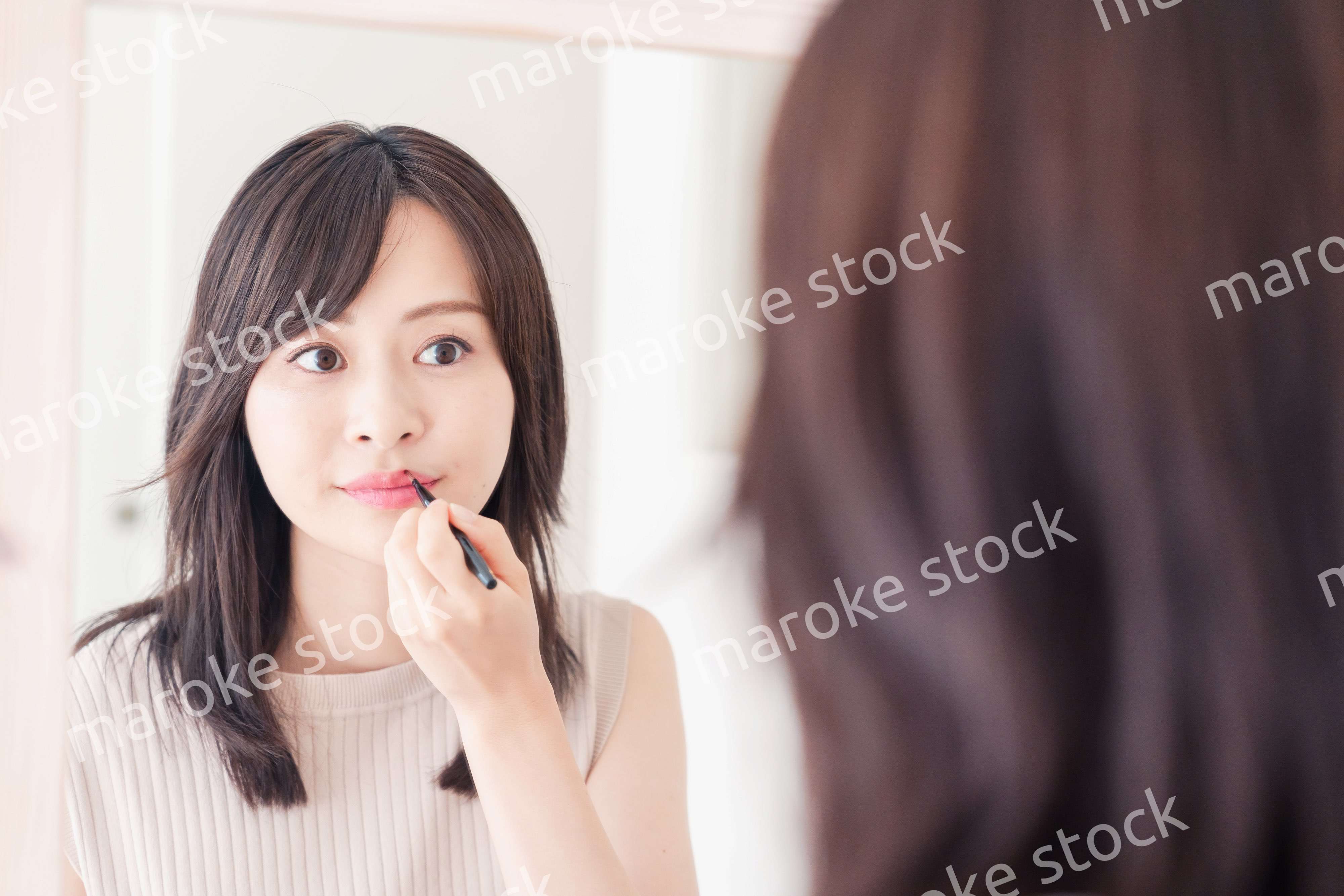 家でメイクをする若い女性