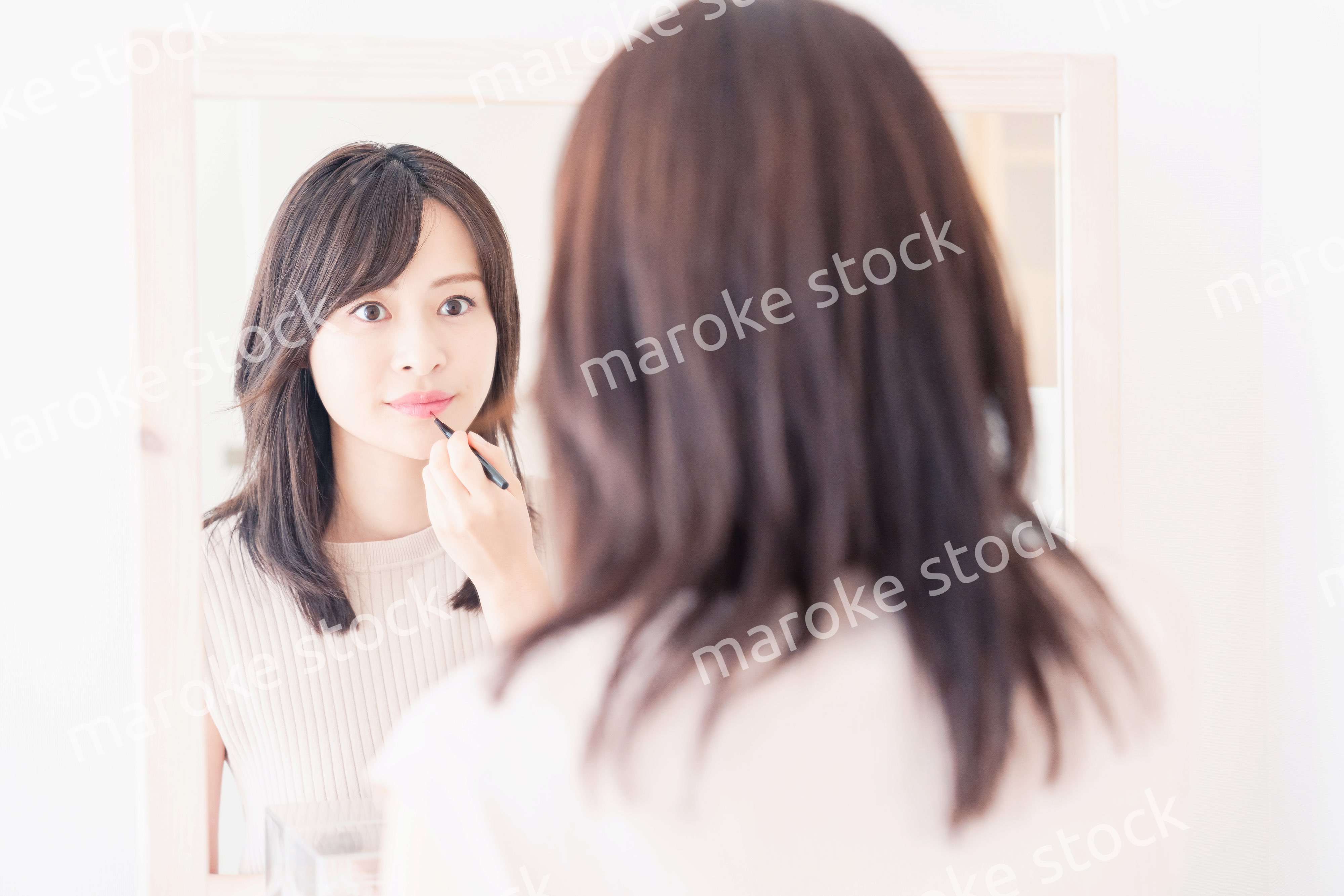 家でメイクをする若い女性