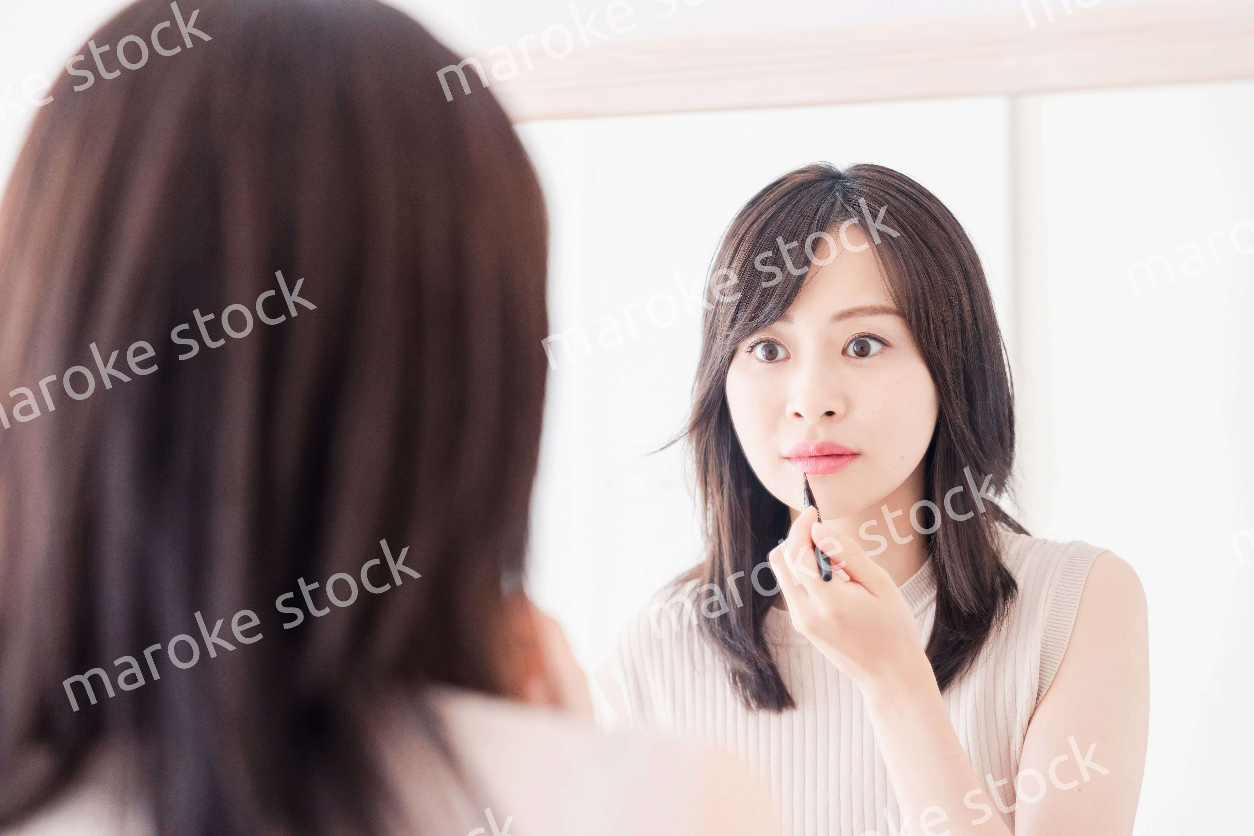 家でメイクをする若い女性