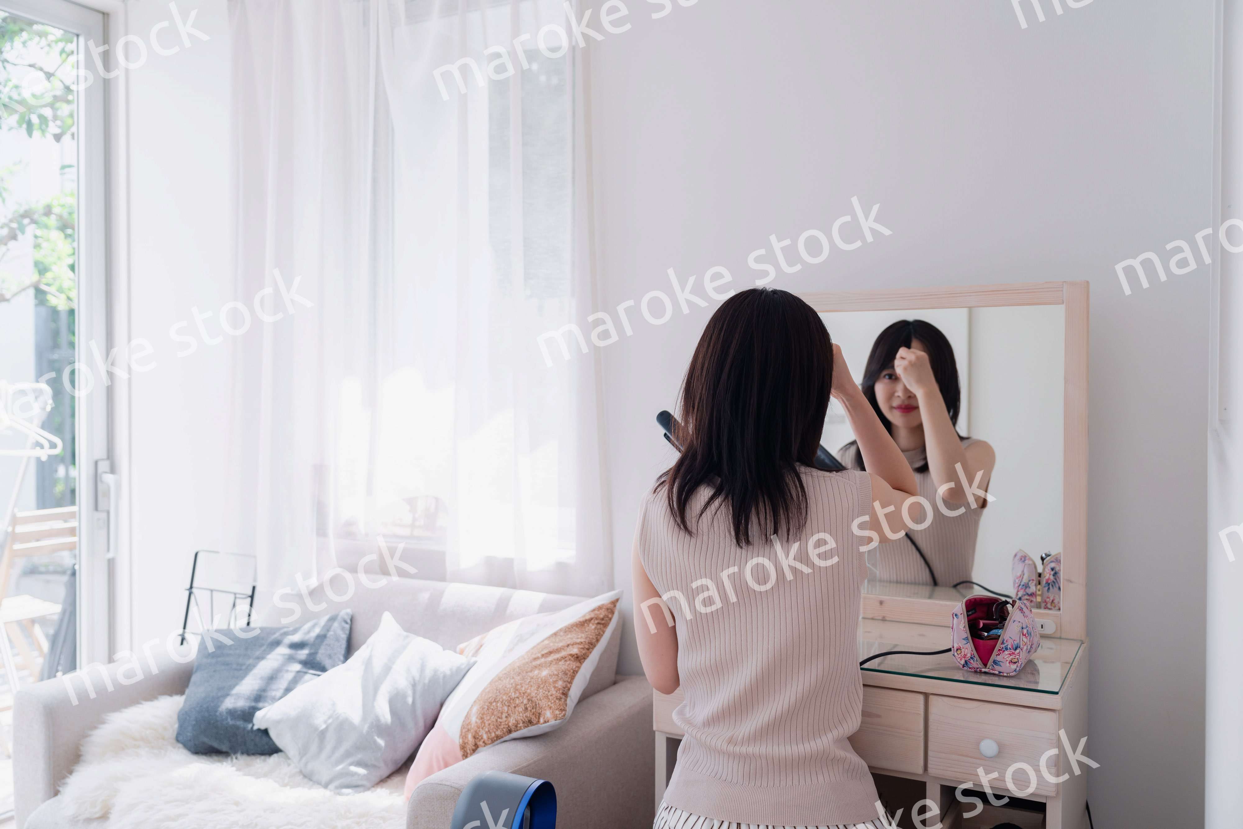 ヘアアイロンを使って髪をセットする若い女性