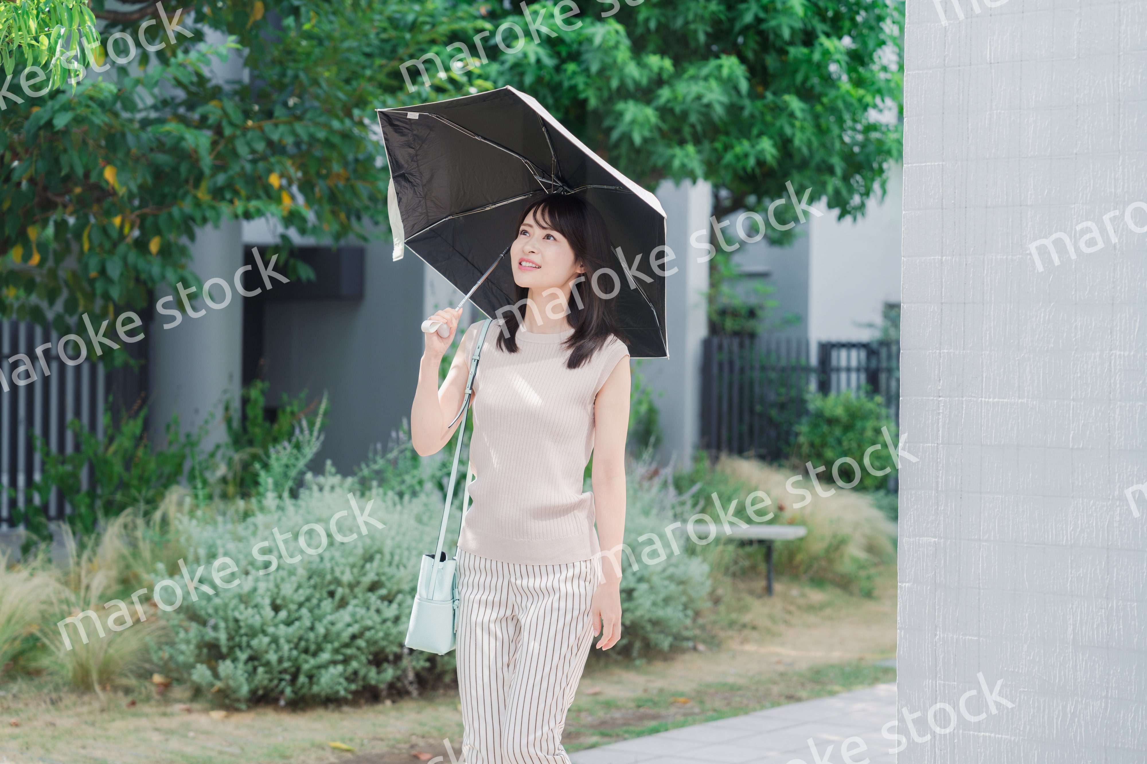 日傘を差して外を歩く若い女性