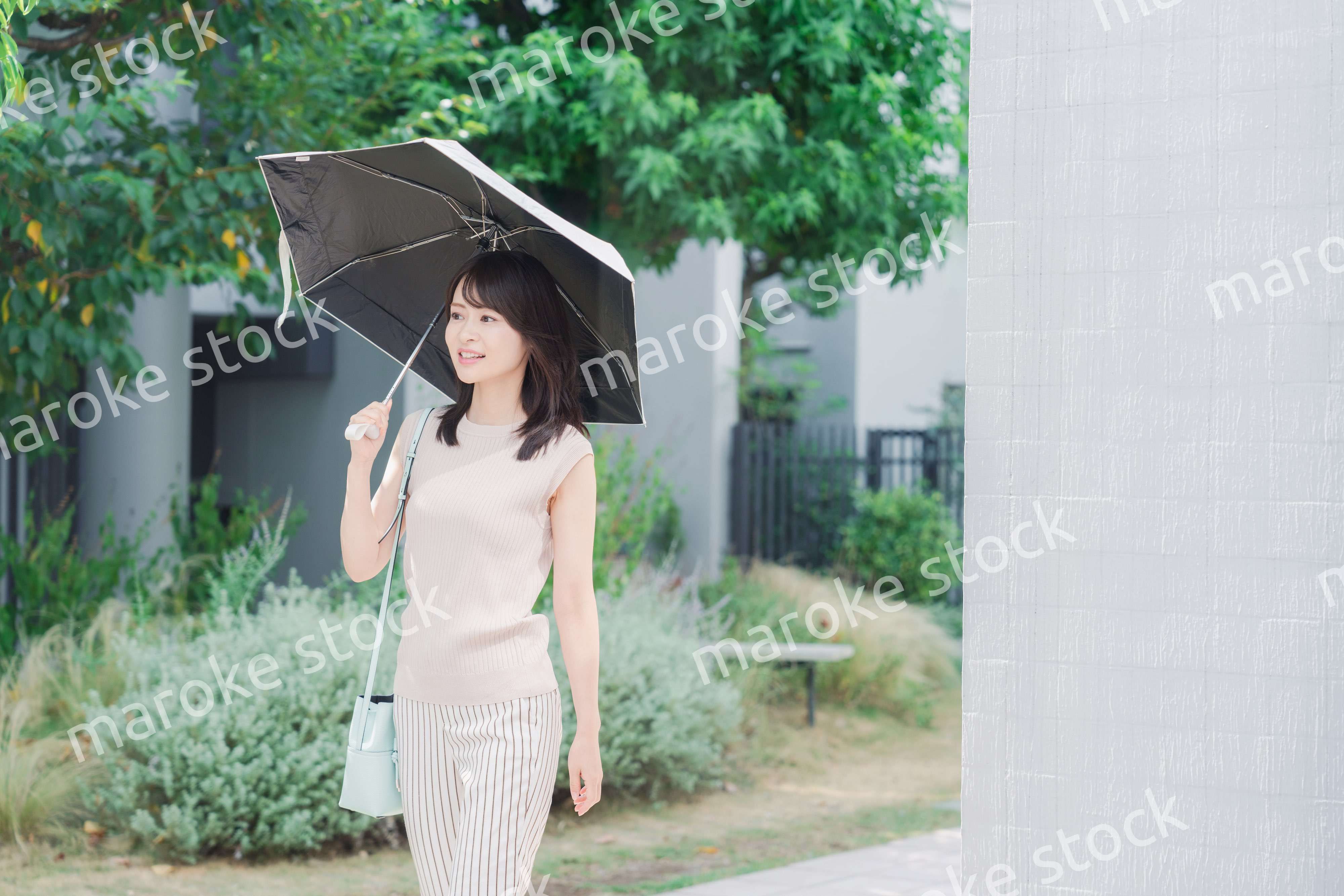 日傘を差して外を歩く若い女性