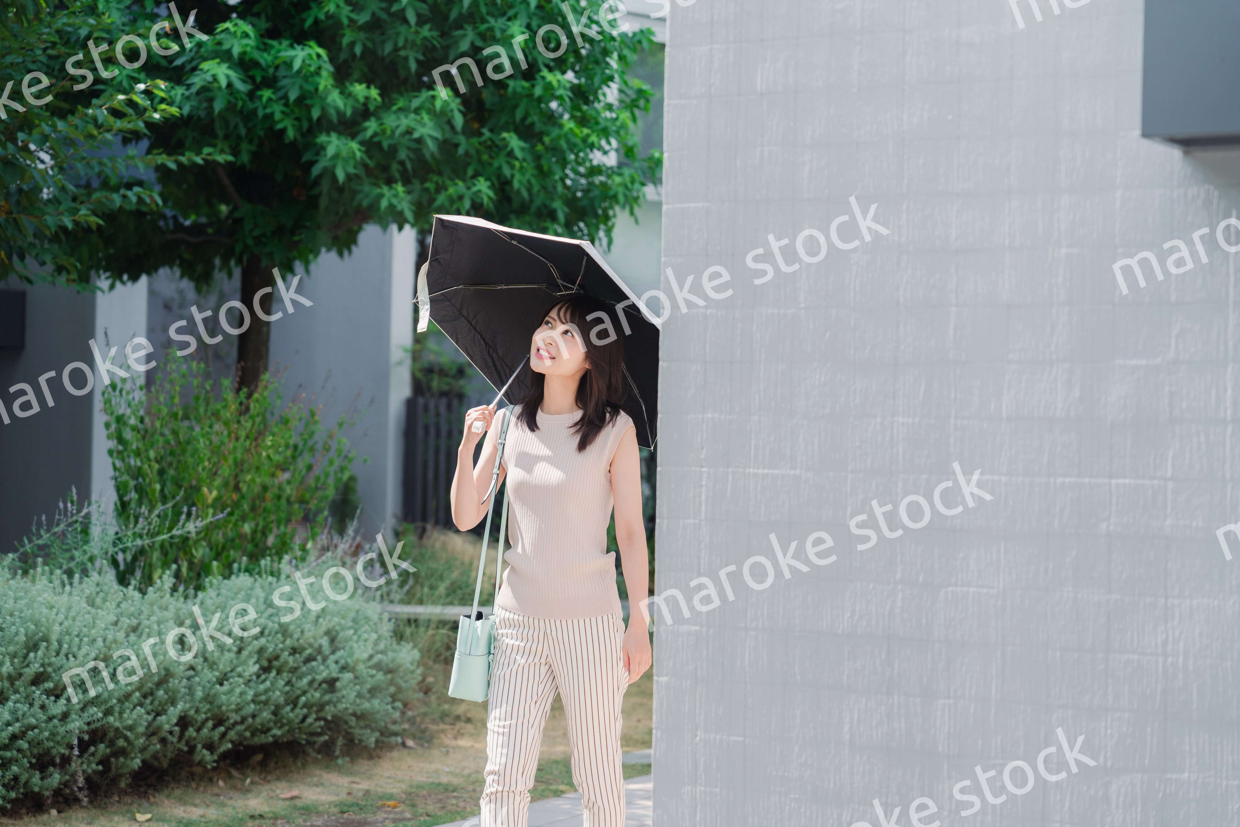 日傘を差して外を歩く若い女性