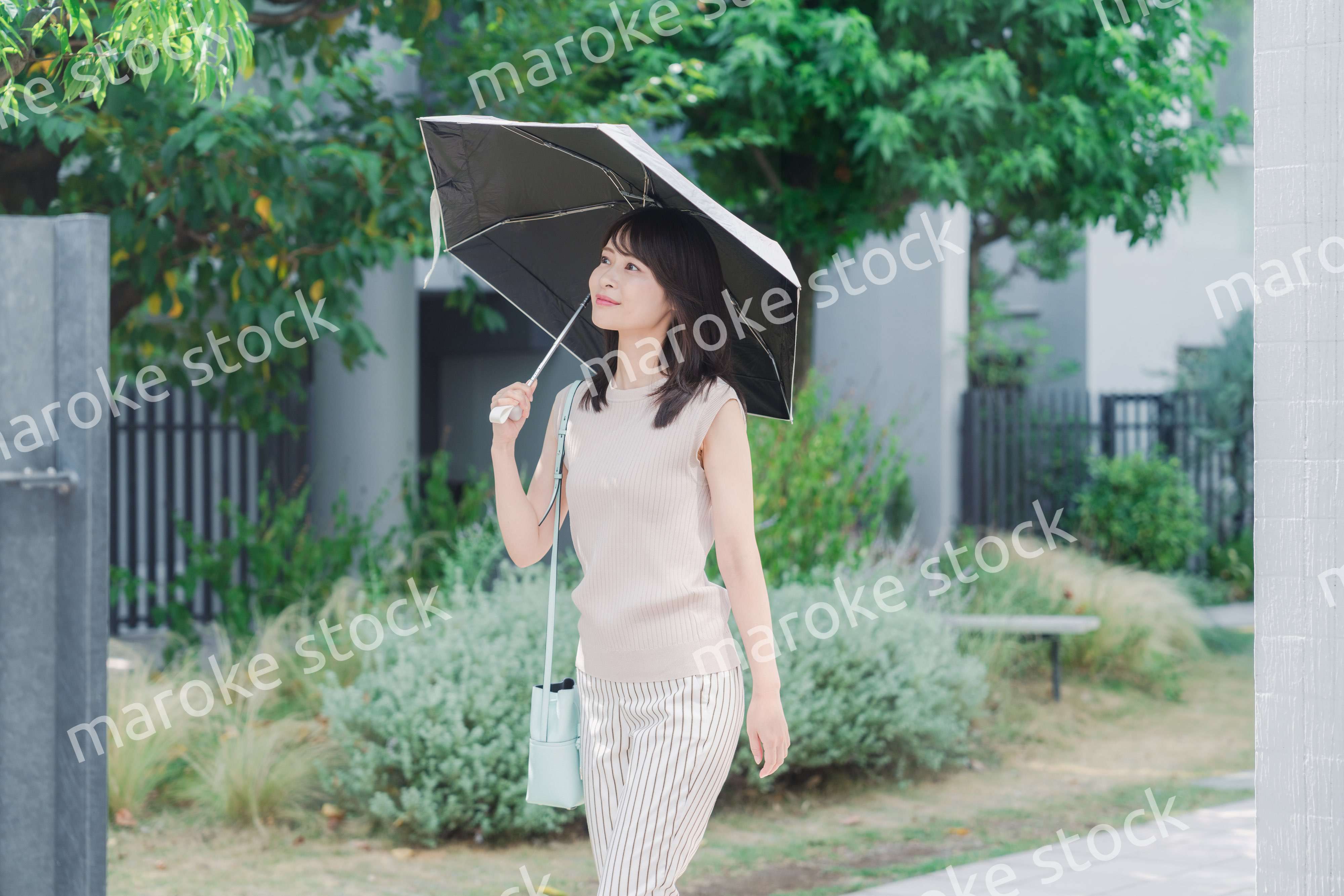 日傘を差して外を歩く若い女性