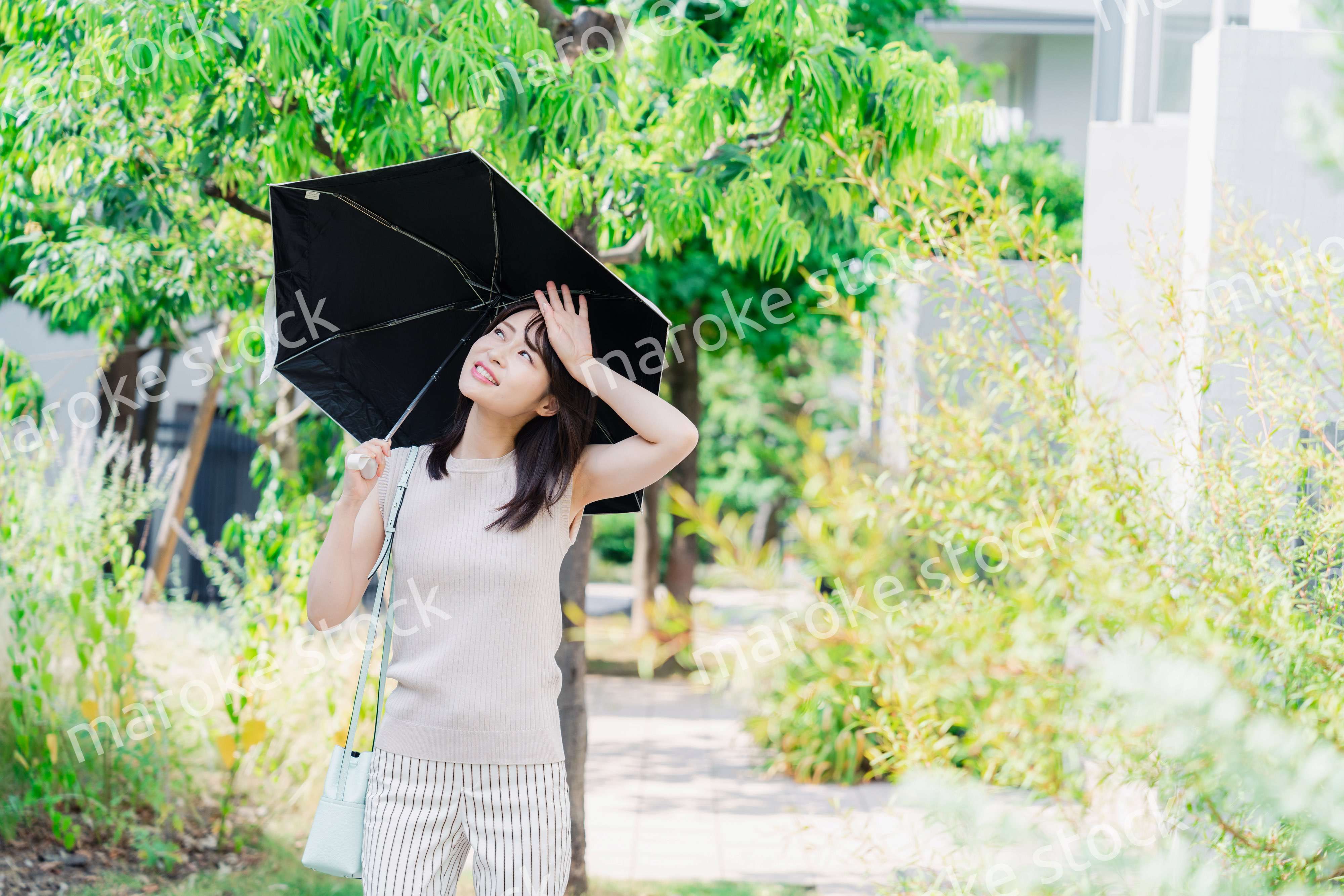 日傘を差して外を歩く若い女性