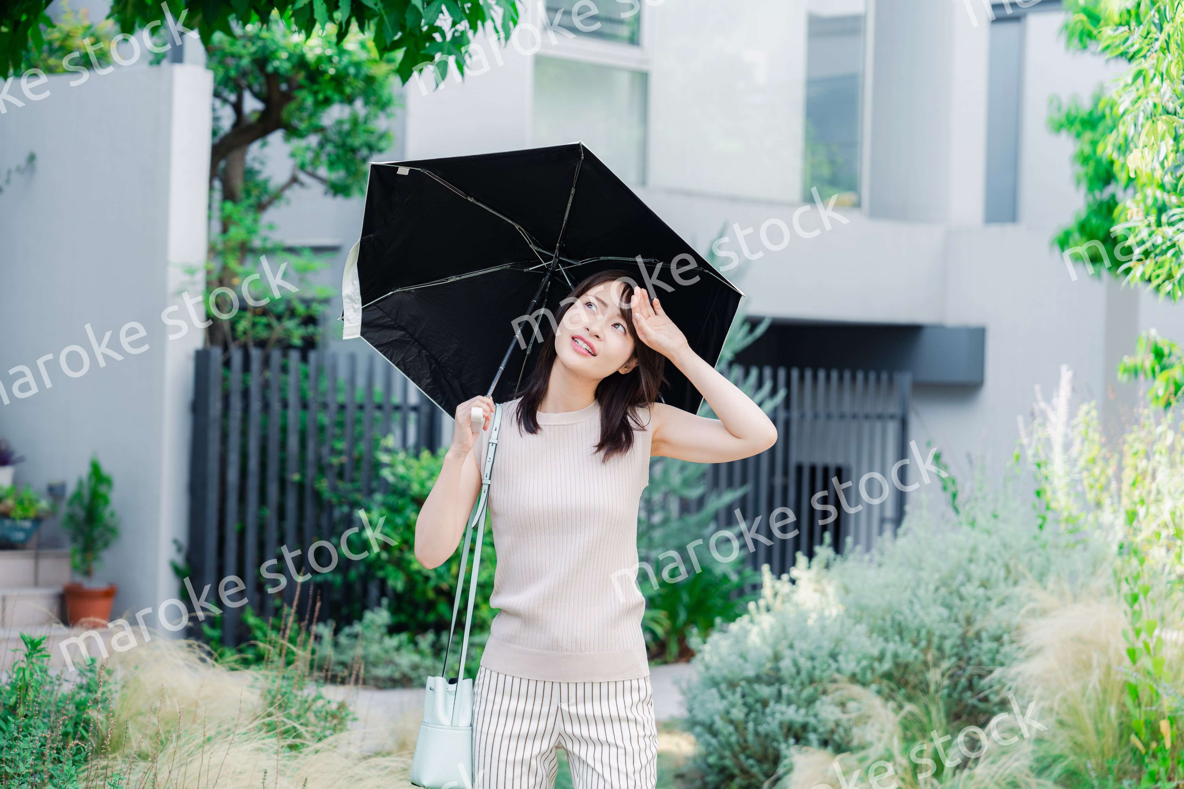 日傘を差して外を歩く若い女性