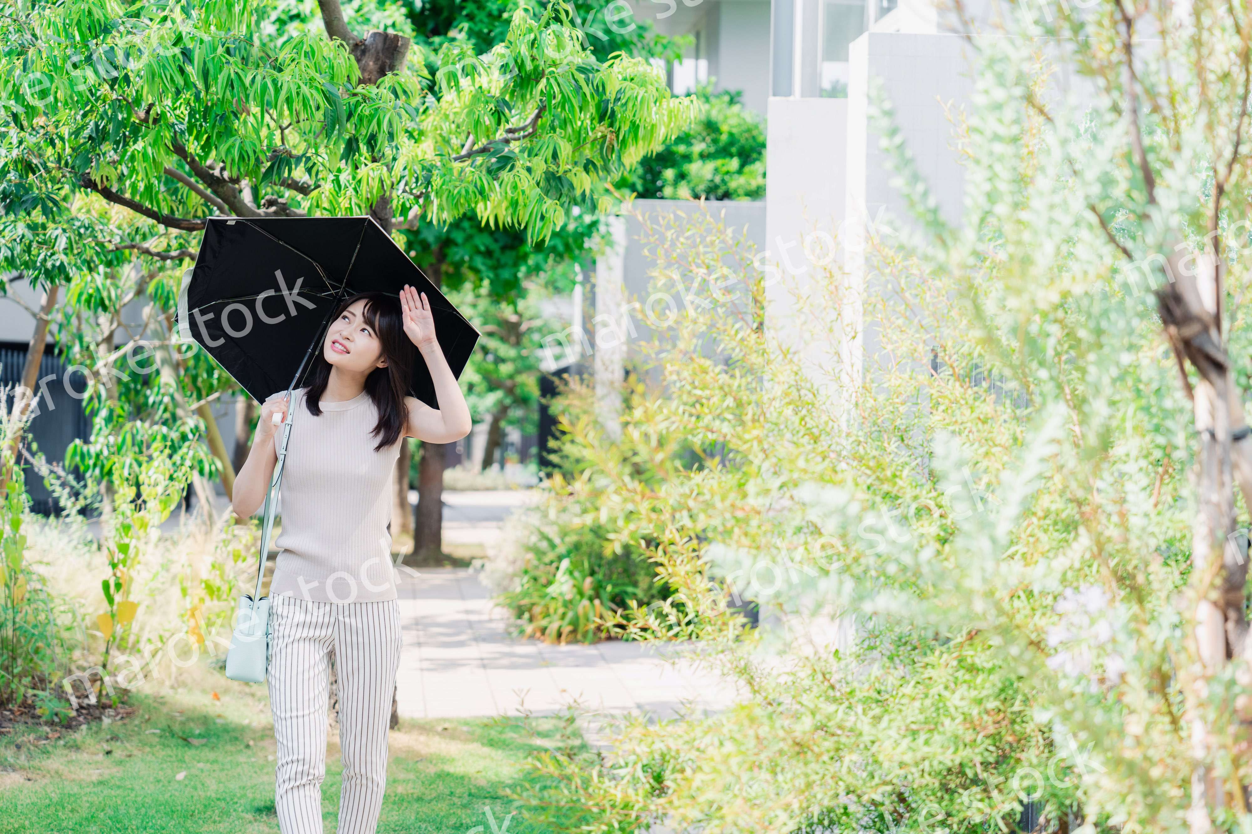 日傘を差して外を歩く若い女性