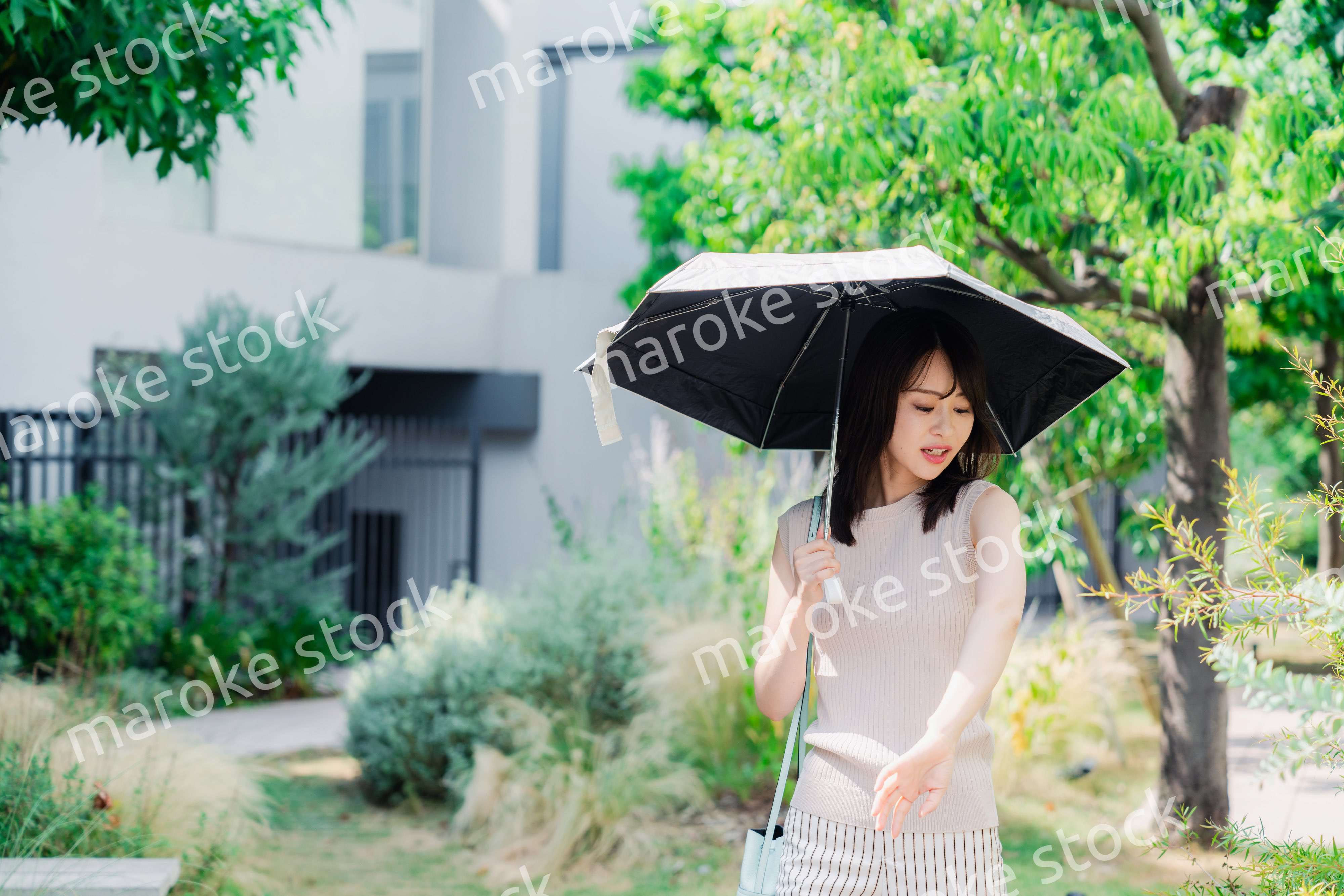 日傘を差して外を歩く若い女性