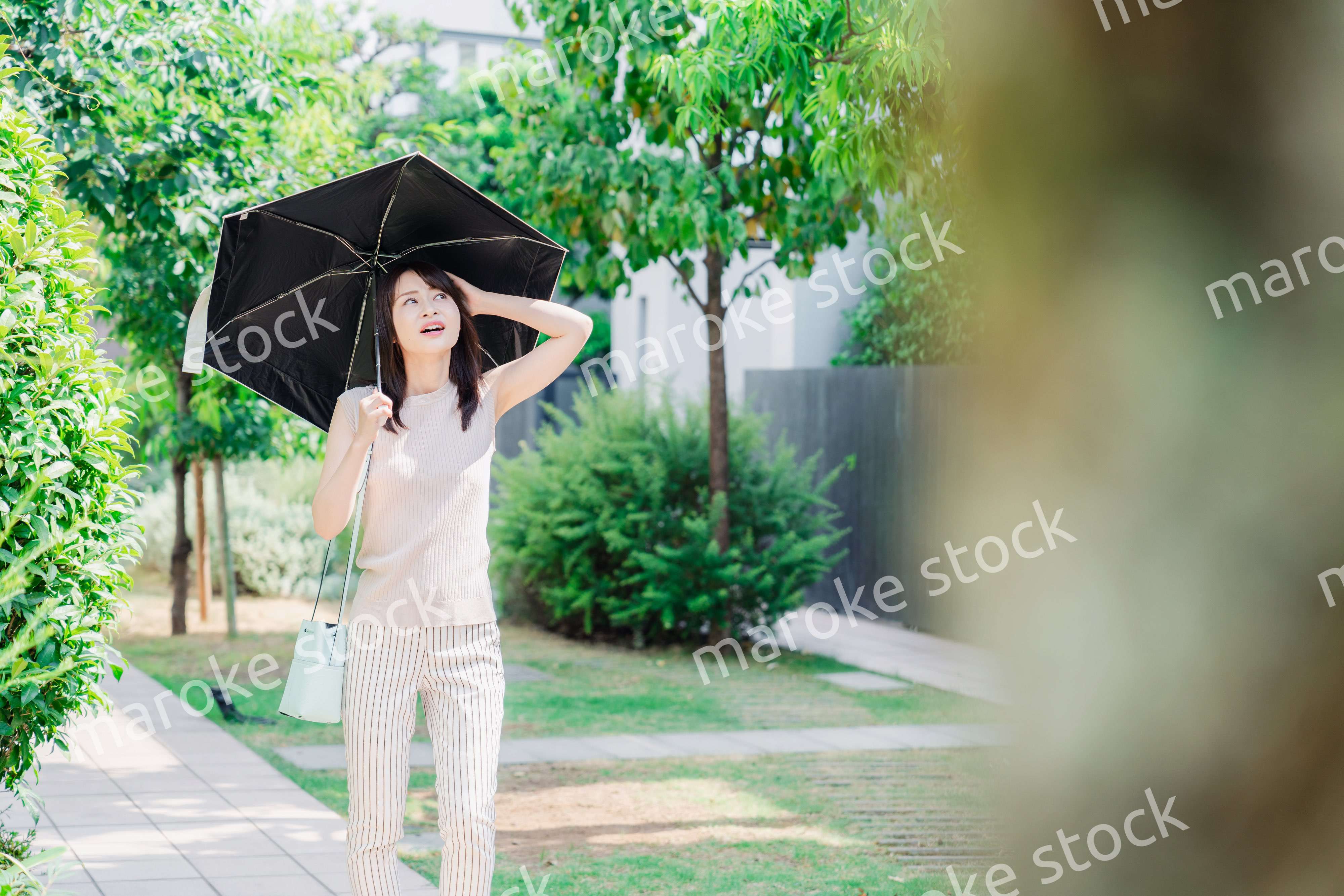 日傘を差して外を歩く若い女性