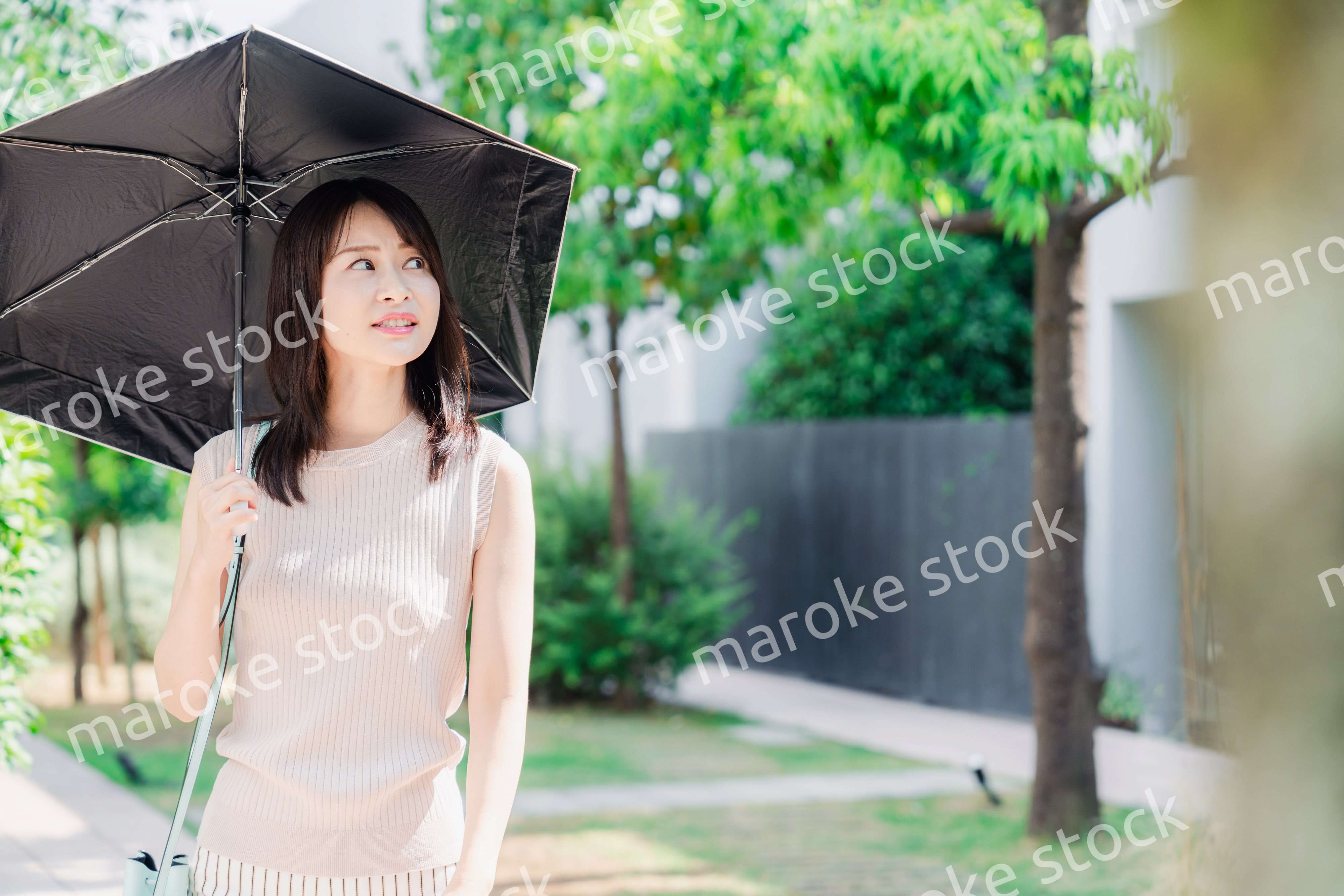 日傘を差して外を歩く若い女性