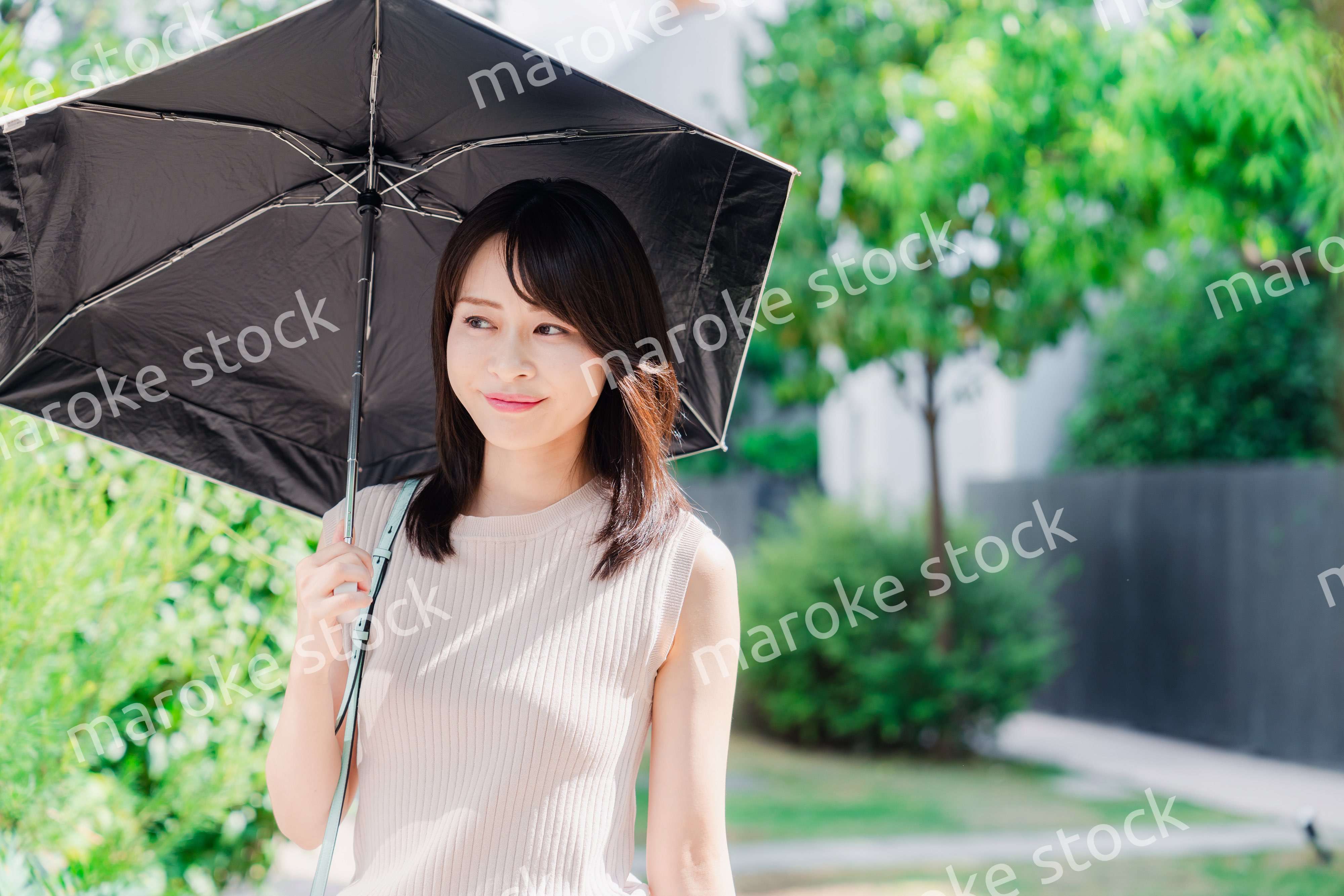 日傘を差して外を歩く若い女性