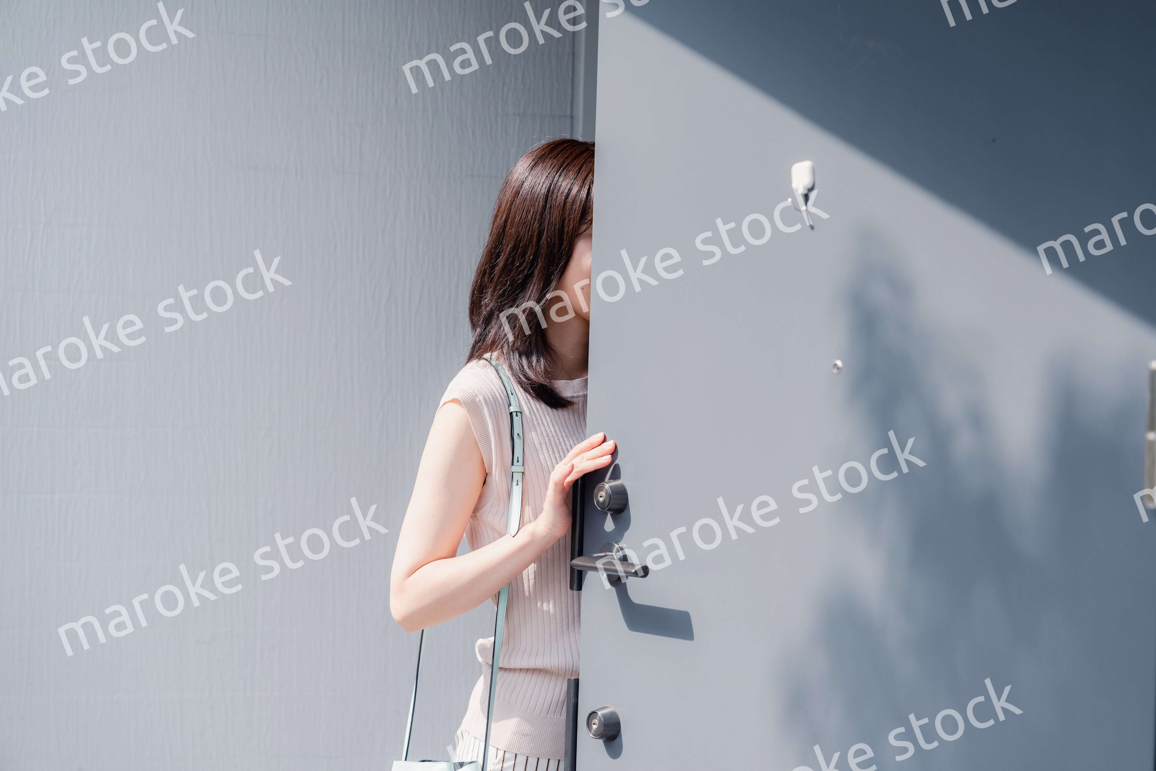 家の玄関ドアを開ける若い女性